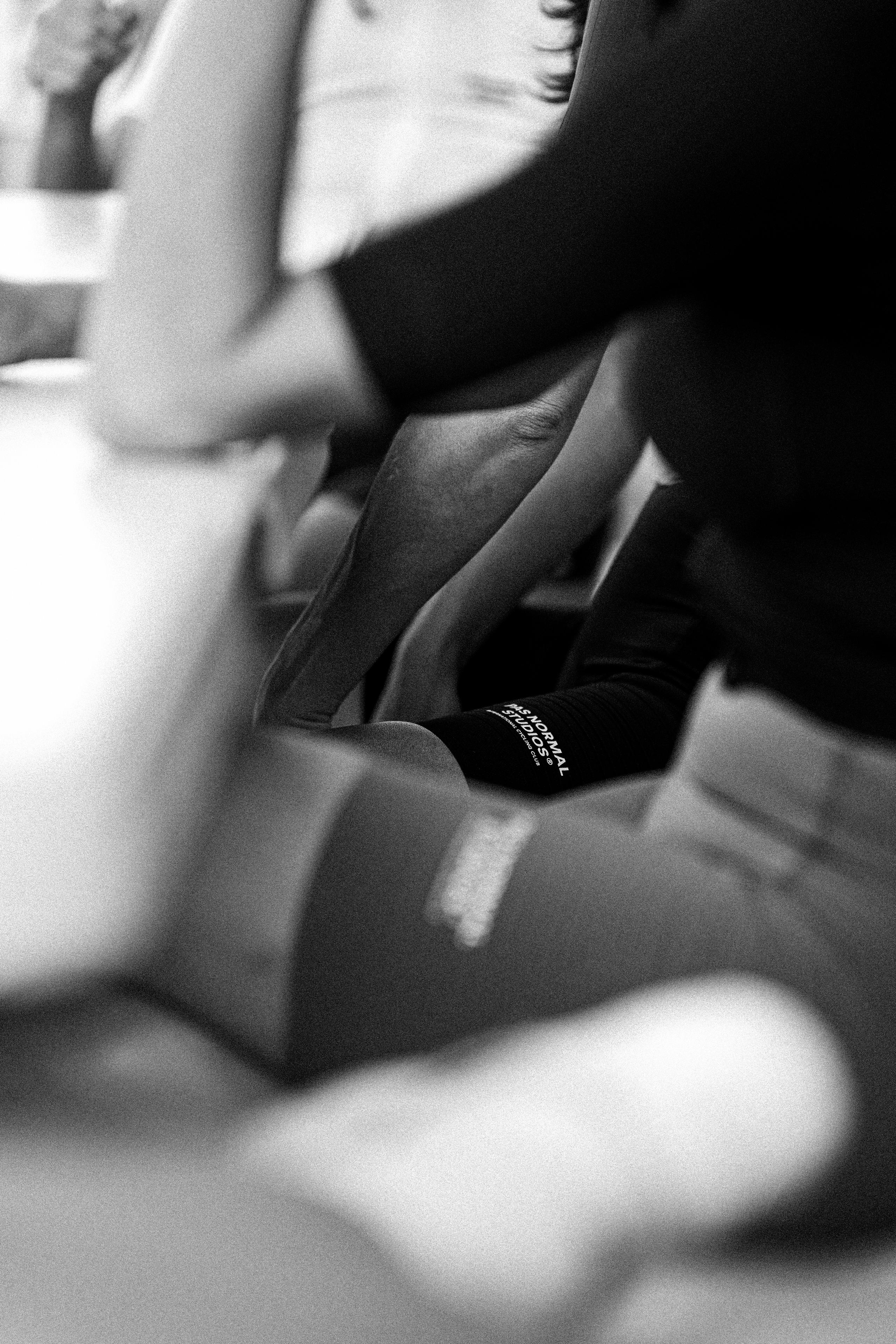 Black and white close-up of cyclist's legs wearing black cycling shorts with logo detail