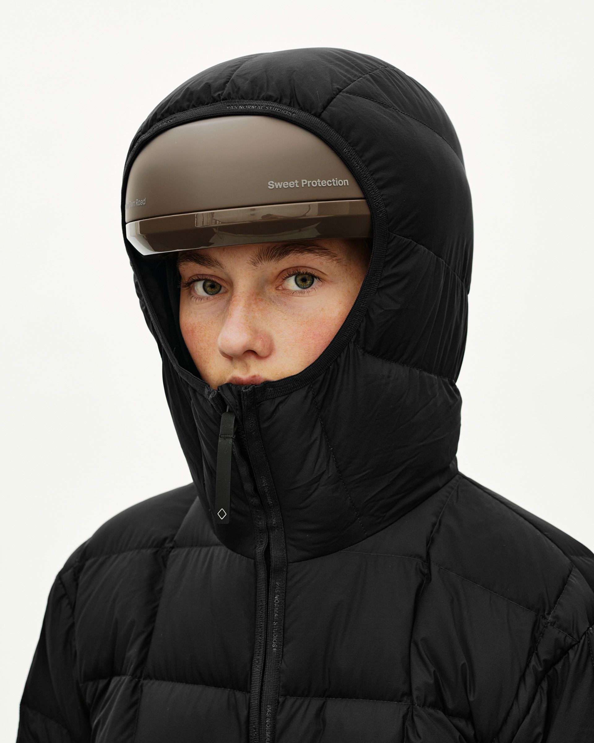 Black Off-Race Down Liner Jacket on model with hood up and Sweet Protection cycling helmet worn over hood