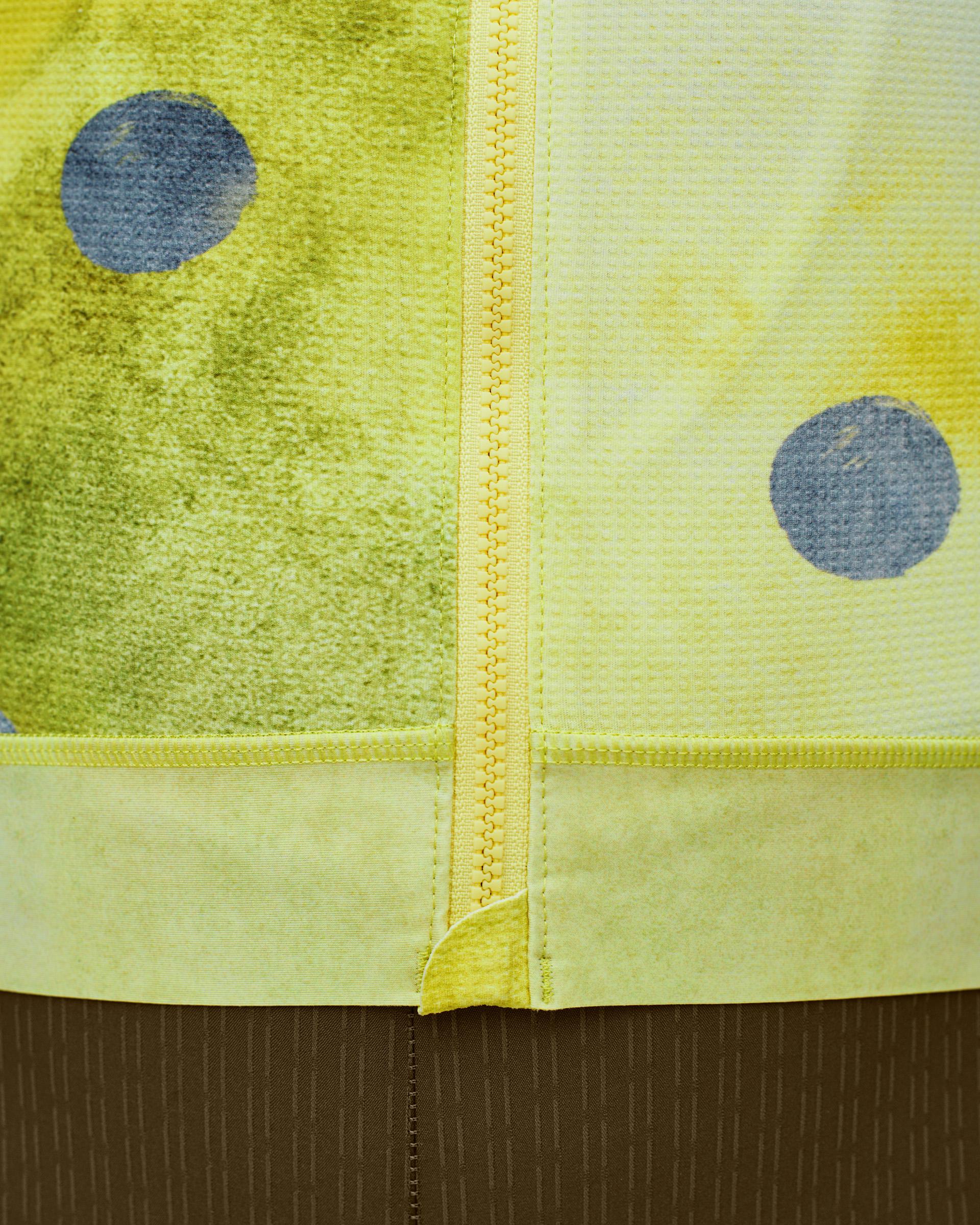 Yellow T.K.O. Essential Light cycling jersey, detail view of front zip with blue dot pattern