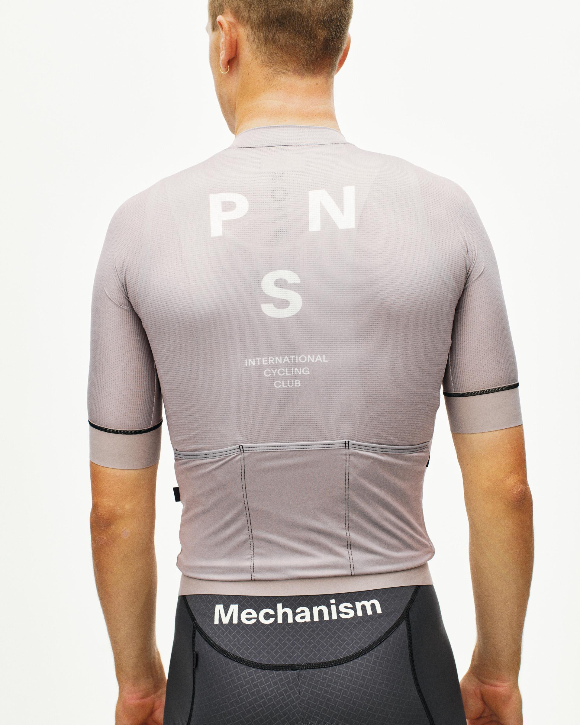 Grey Mechanism cycling jersey on model, rear view with white PNS back print and three rear pockets