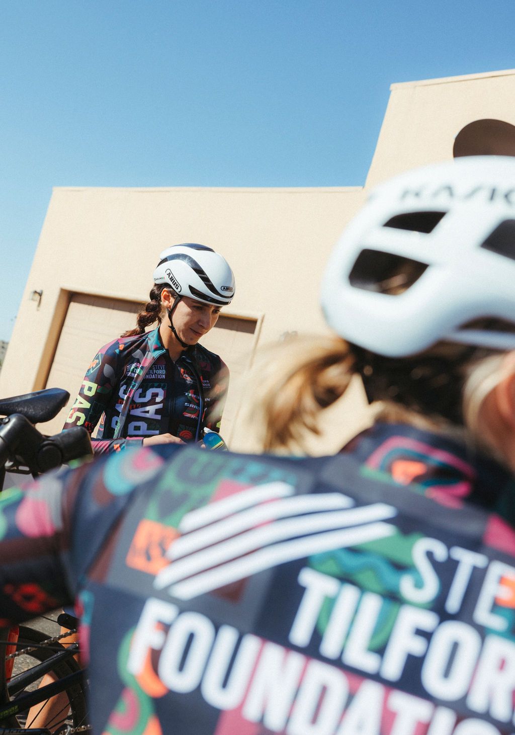 Model wearing dark jersey with colorful geometric pattern and time trial helmet at cycling event
