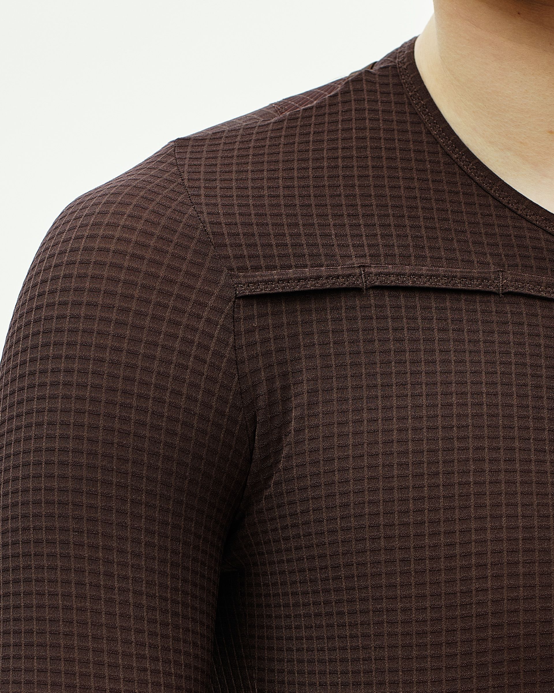 Brown textured fabric with grid pattern and flat seam construction on cycling garment shoulder and chest