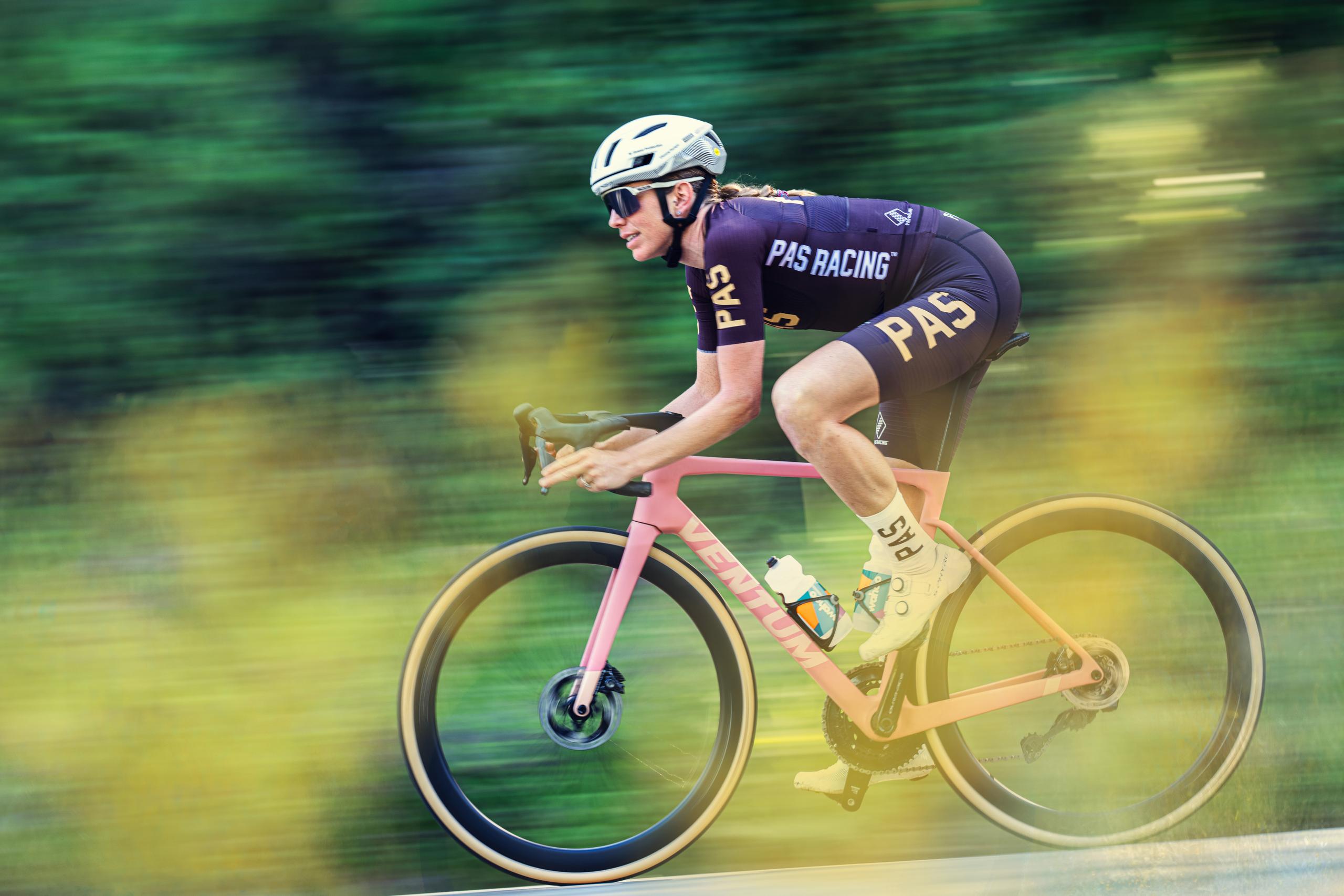 Cyclist in purple PAS Racing kit racing on time trial bike with motion blur background