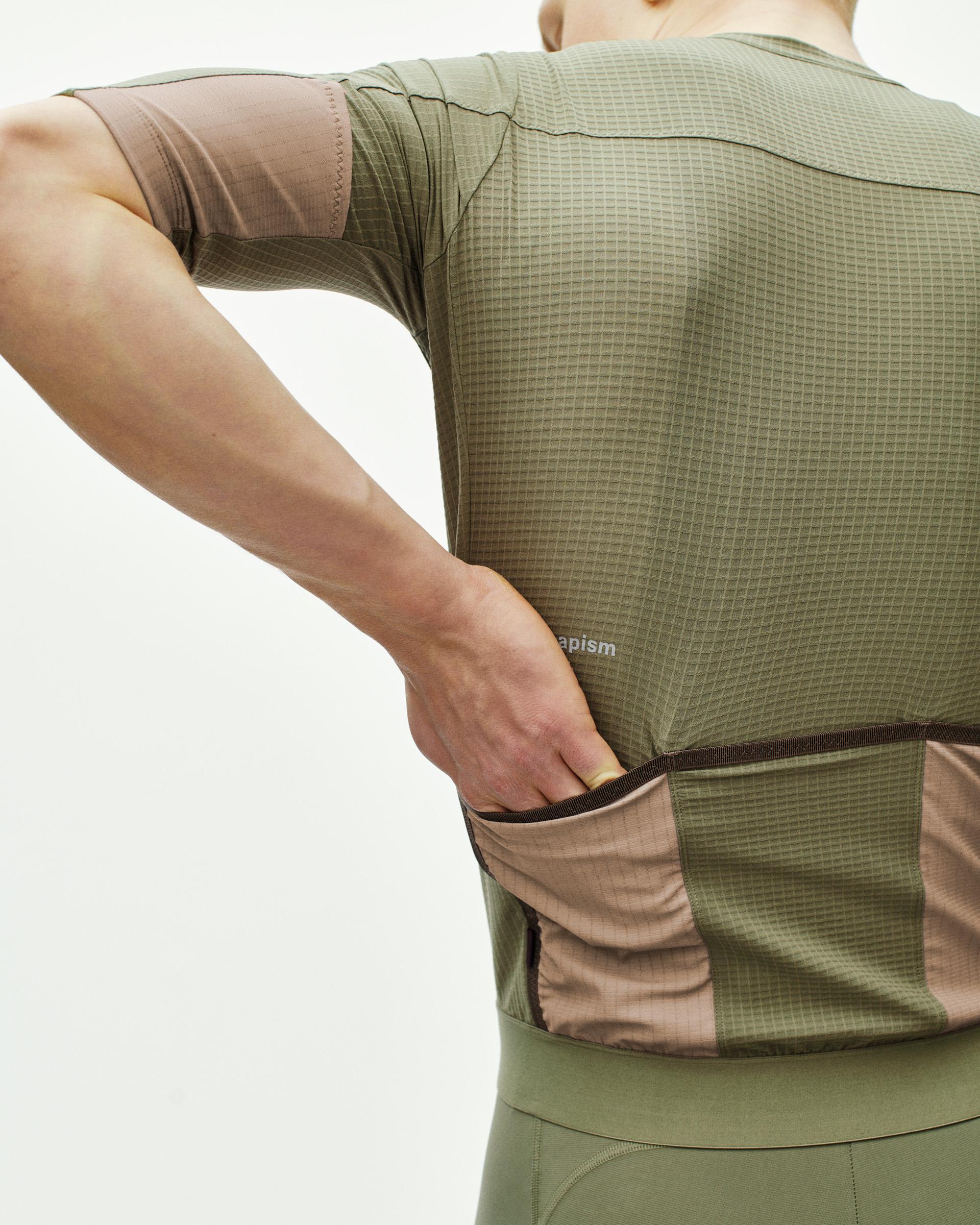 Light Olive Escapism cycling jersey on model, rear view with contrast side panels and rear pockets