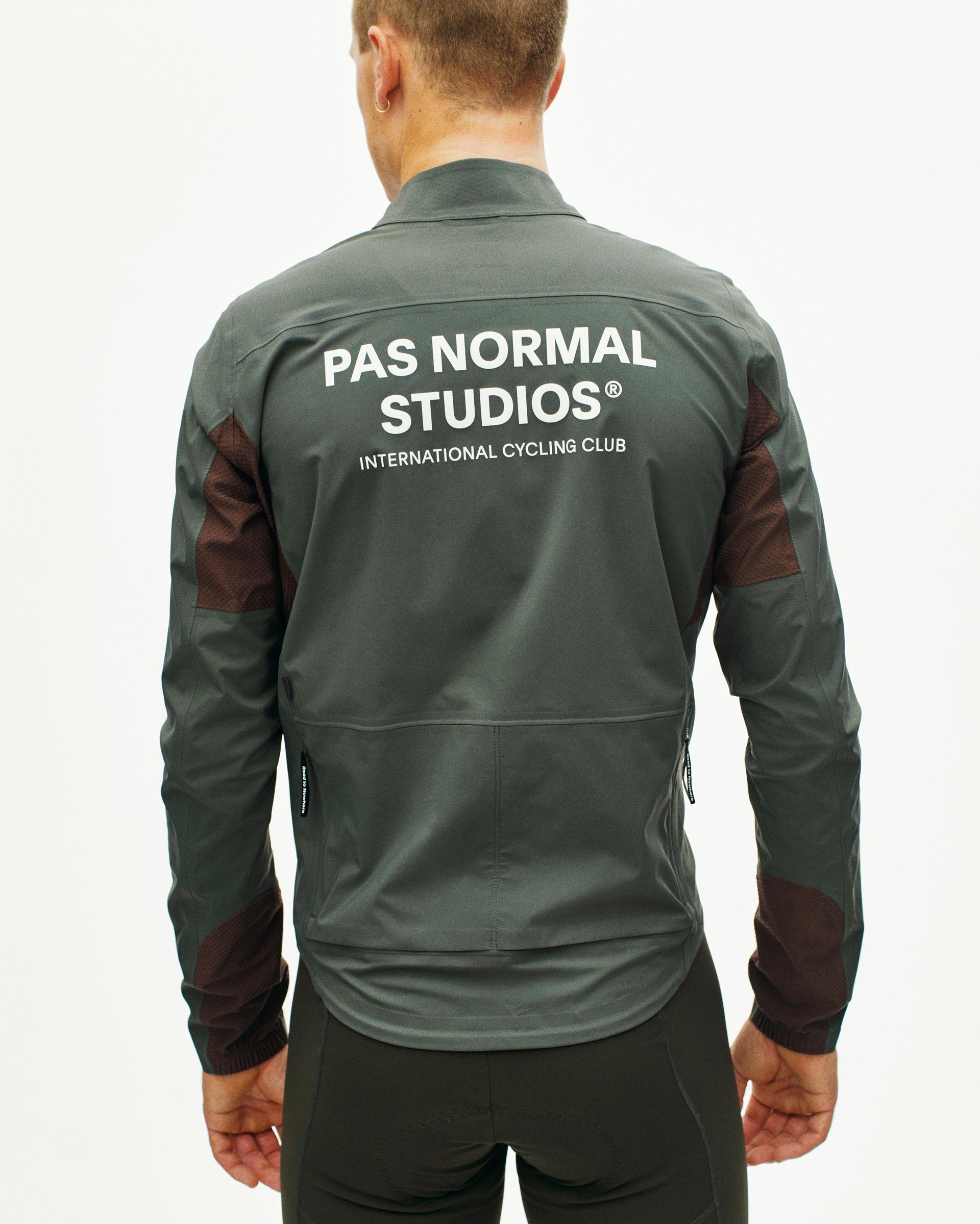 Dark Grey Mechanism Shell cycling jacket on model, rear view with white back print and dark mesh sleeve panels