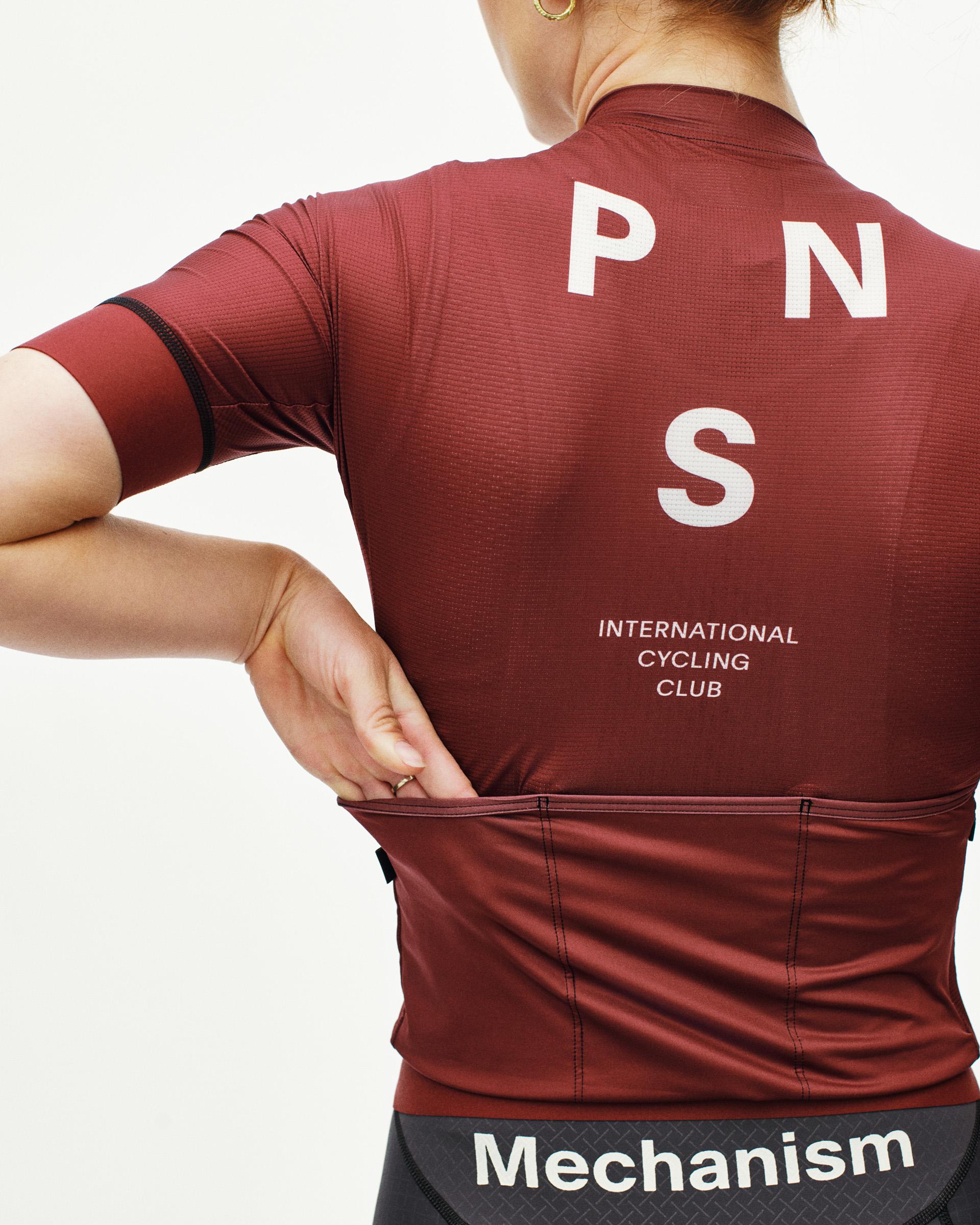 Maroon Mechanism cycling jersey on model, rear view with white PNS logo and International Cycling Club text