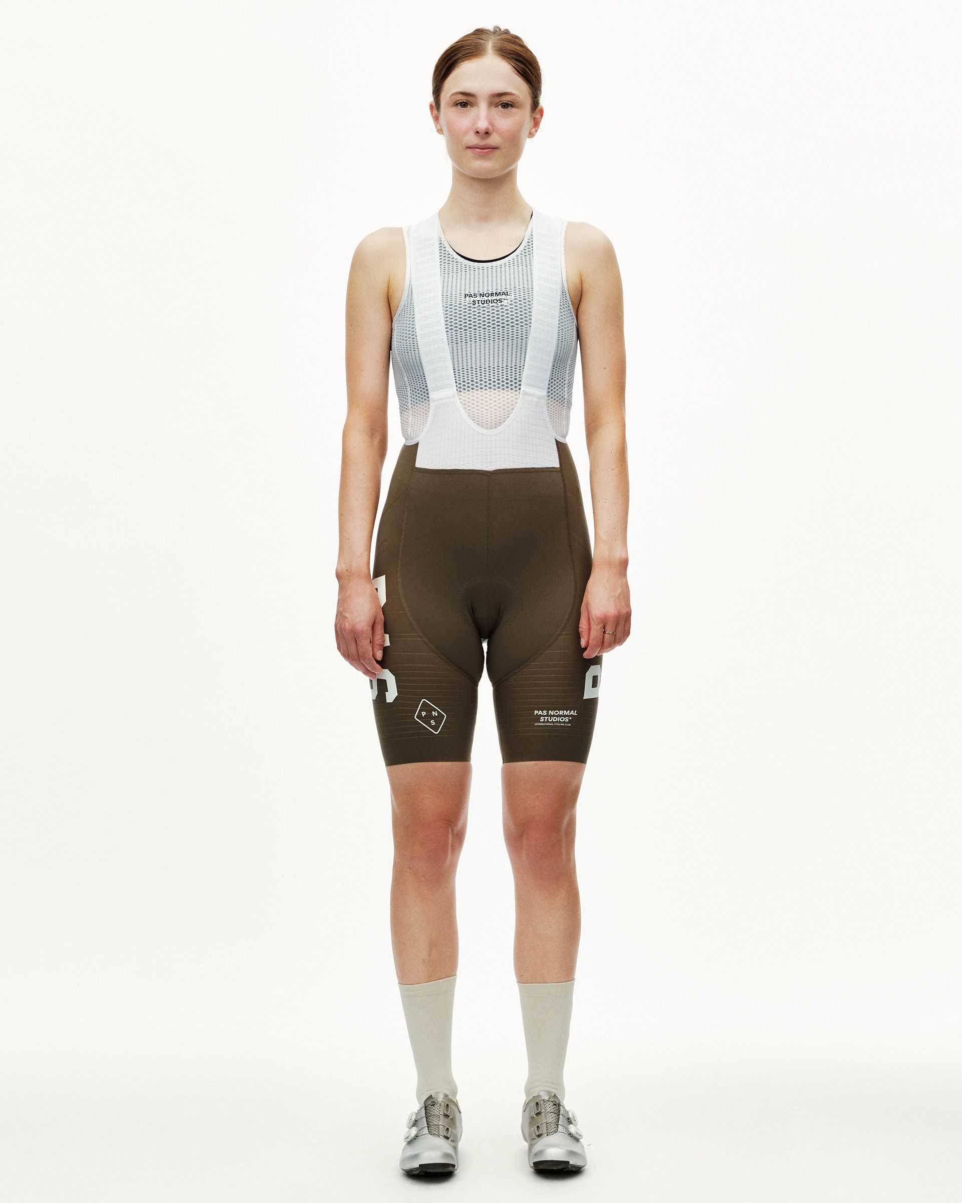 Dark Earth khaki PAS Mechanism Pro women's cycling bibs on model, front view with white mesh bib straps and logo print