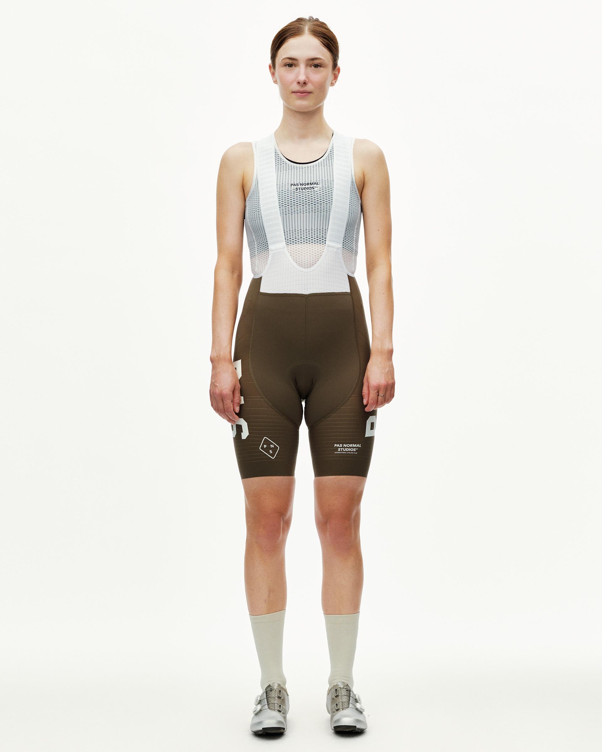 Dark Earth khaki PAS Mechanism Pro women's cycling bibs on model, front view with white mesh bib straps and logo print