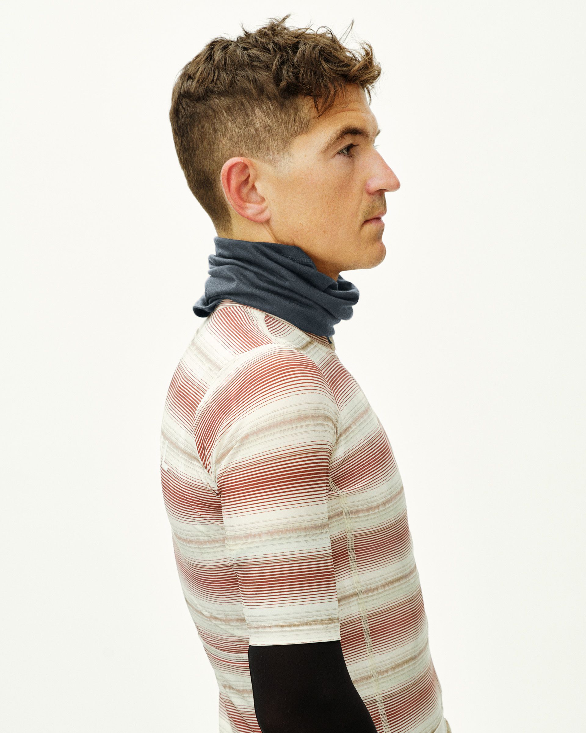 Steel Logo Merino necktube on model, side view with striped cycling jersey