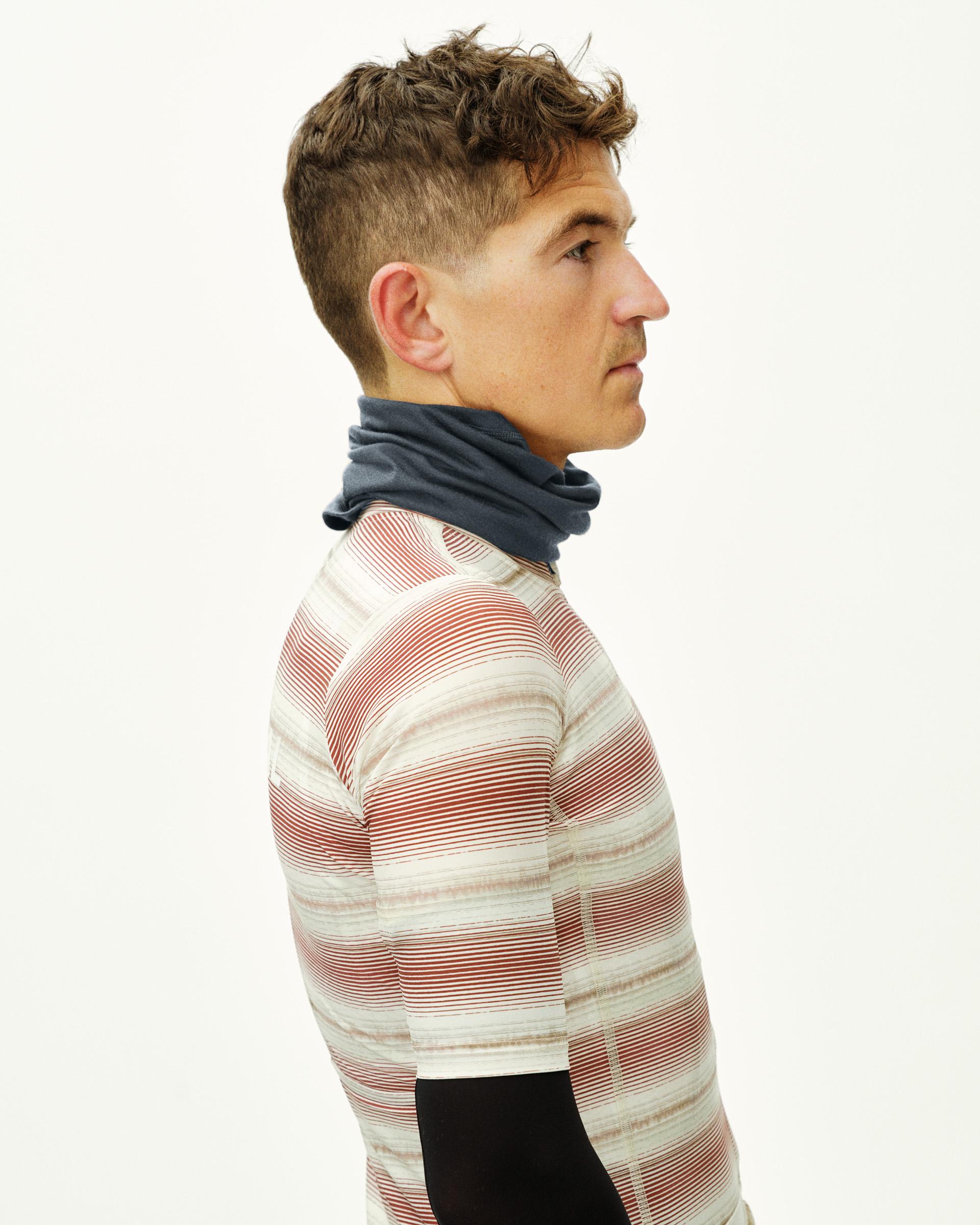 Steel Logo Merino necktube on model, side view with striped cycling jersey