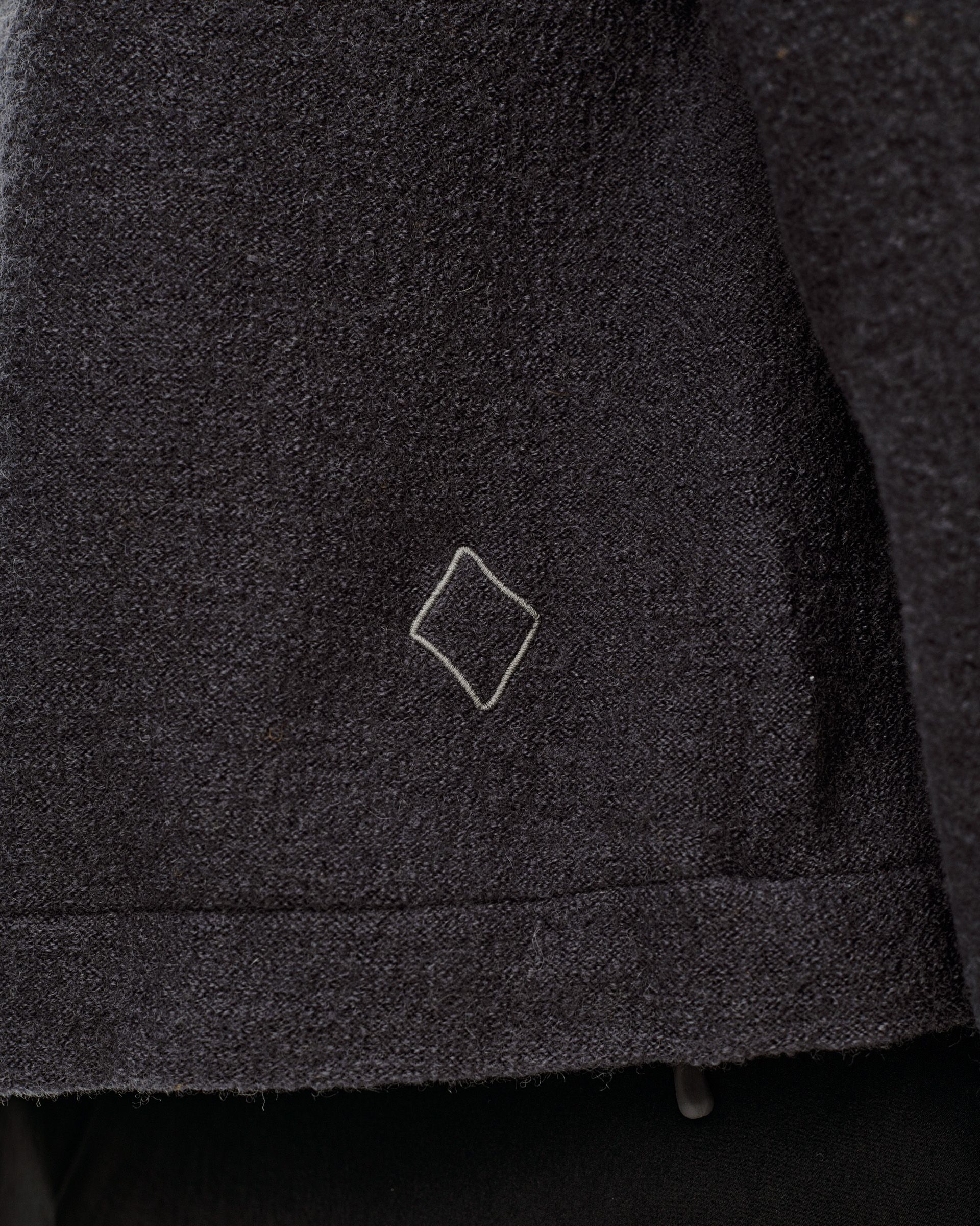 Dark Grey Off-Race Boiled Wool jacket, detail view of hem with embroidered diamond logo
