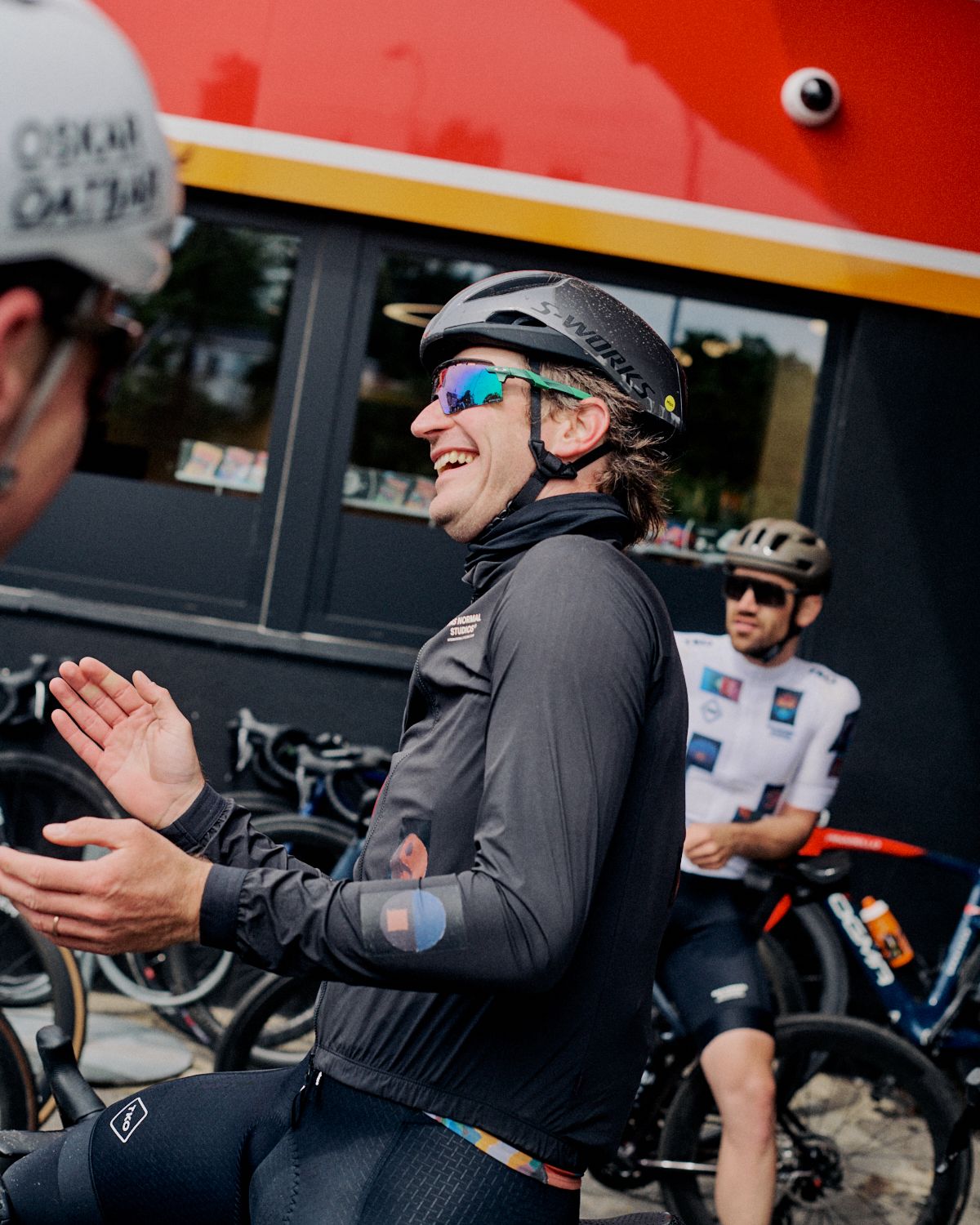 Cyclist in black long sleeve jersey and helmet celebrating with high fives at cycling event