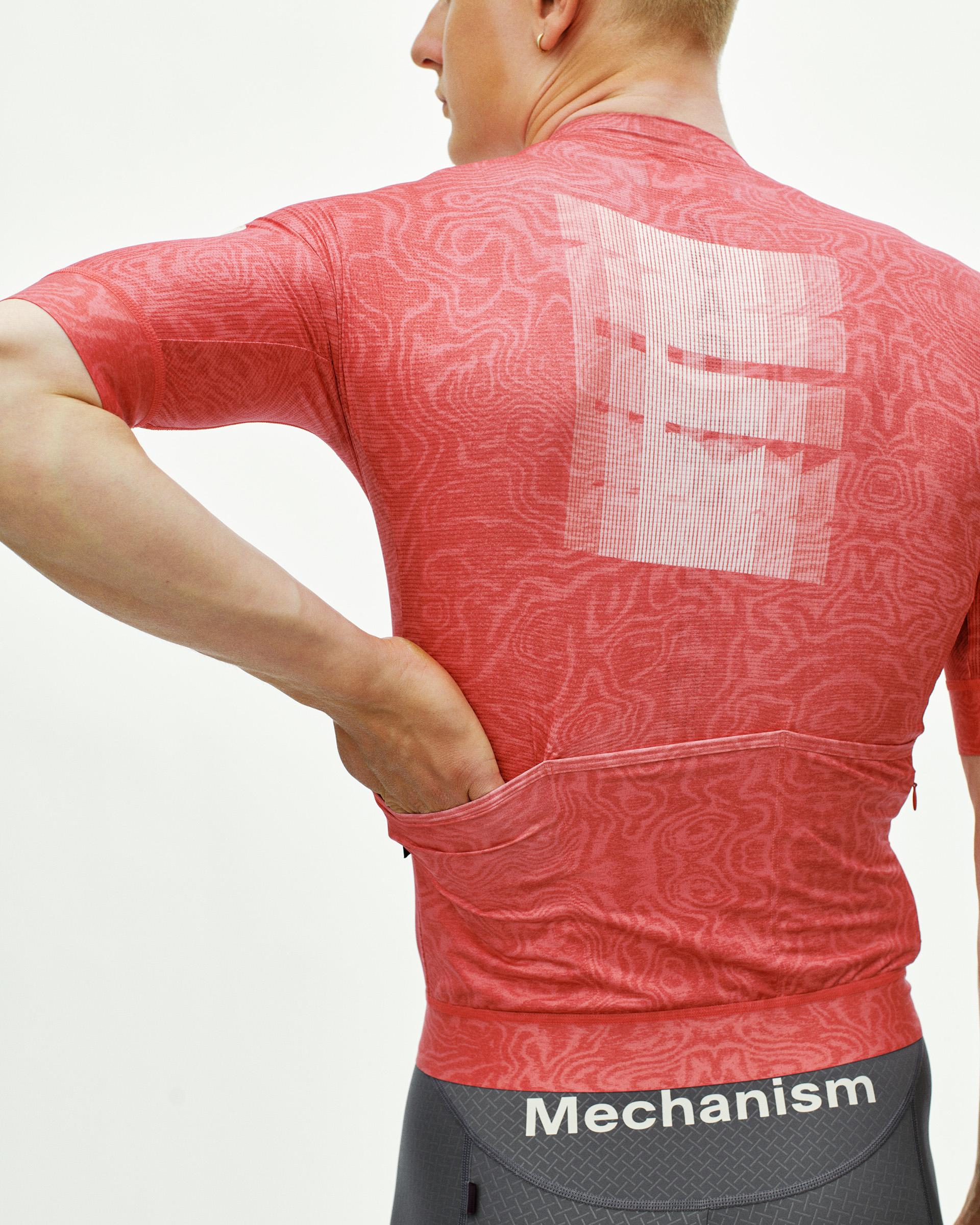 Red Mechanism Logo cycling jersey on model, rear view with tonal all-over print and back pockets