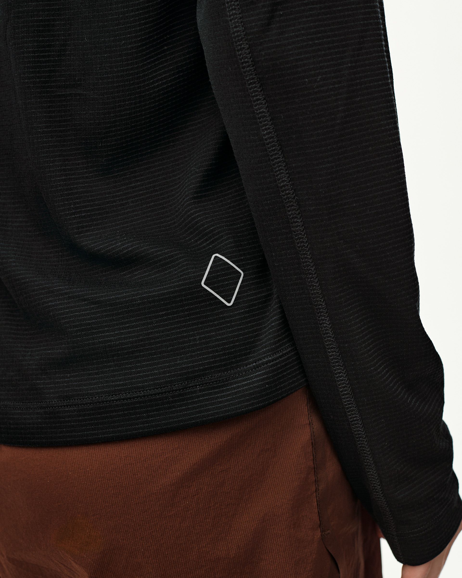 Black Balance long sleeve T-shirt, side detail on model showing ribbed texture and diamond logo at hem