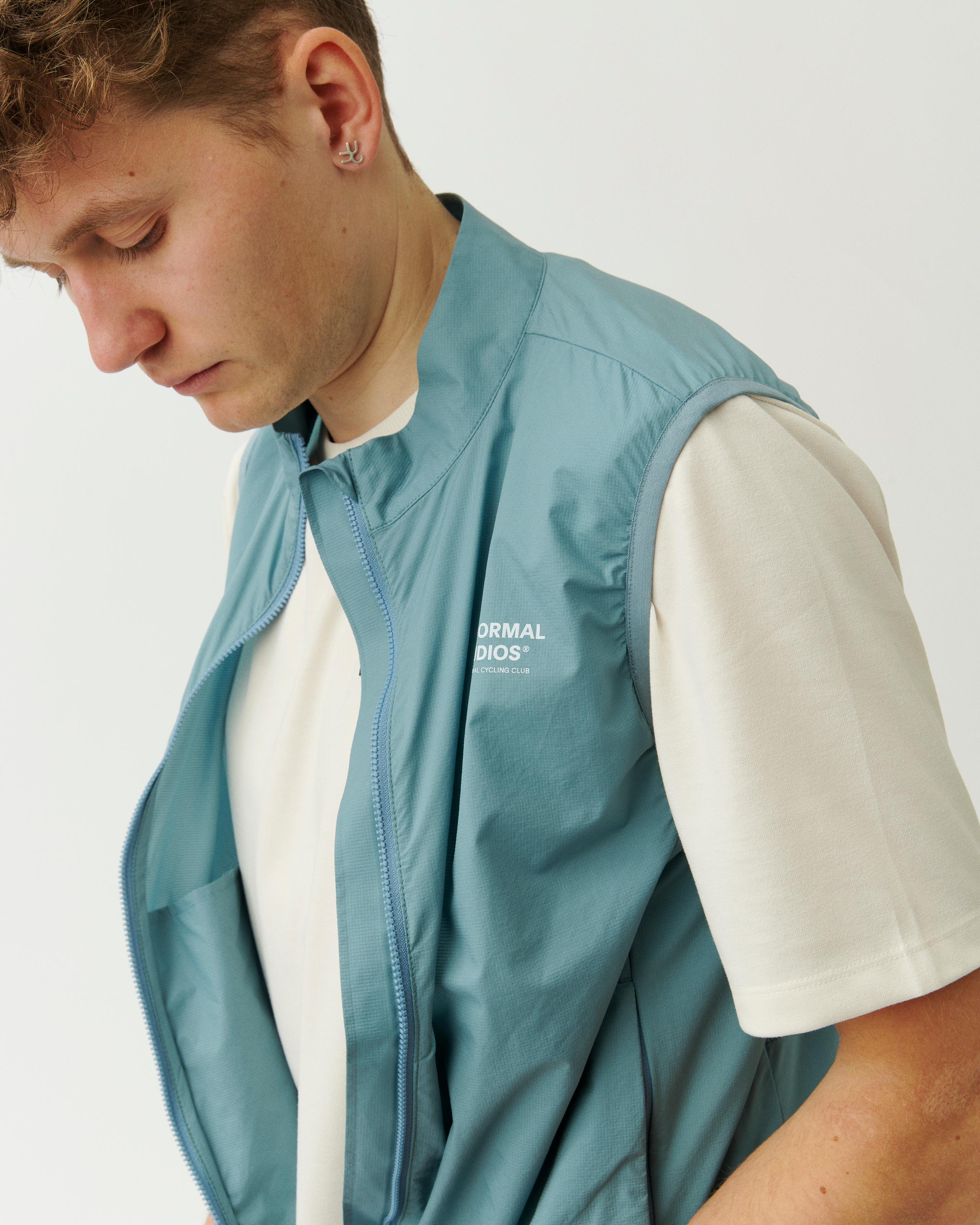 Dusty Blue Off-Race Stow Away vest on model, front detail view with full zip and white chest logo