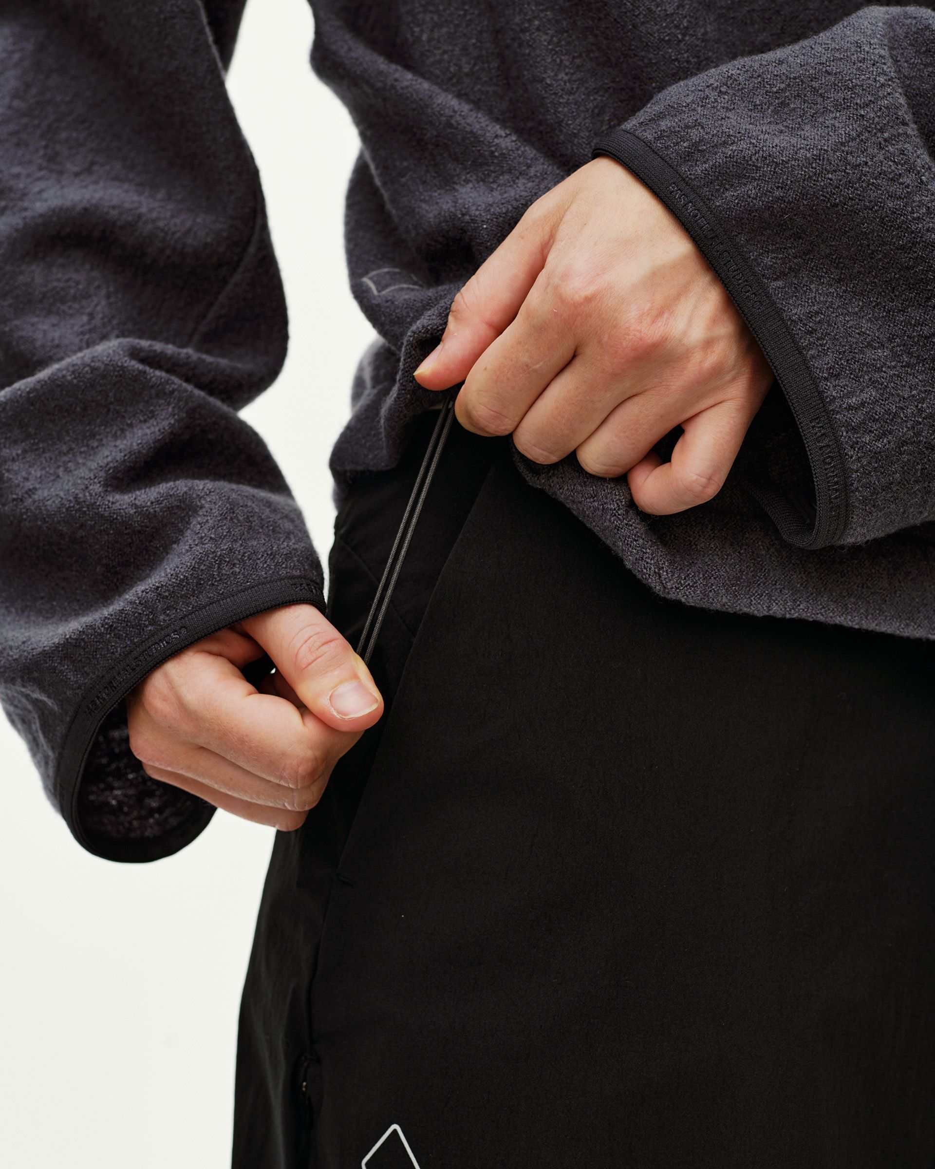 Dark Grey Off-Race Boiled Wool jacket, detail view of model zipping front closure showing fleece texture and ribbed cuffs