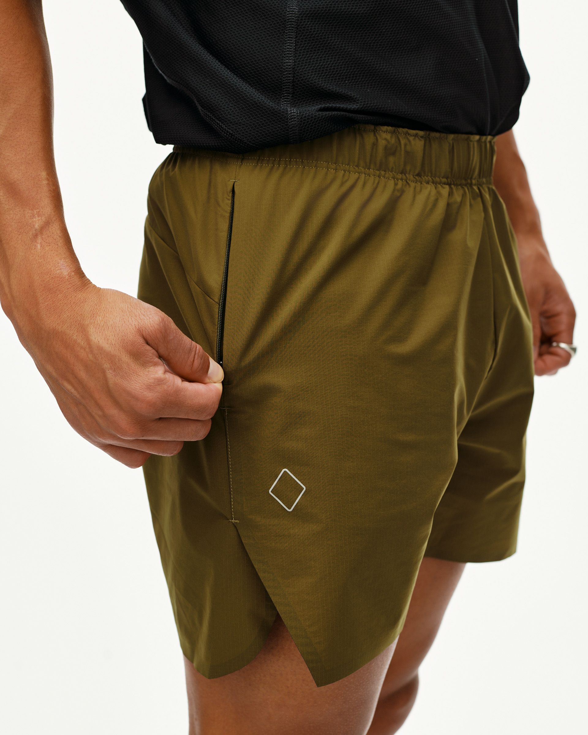 Moss Brown Balance shorts on model, side detail view with zip pocket and diamond logo