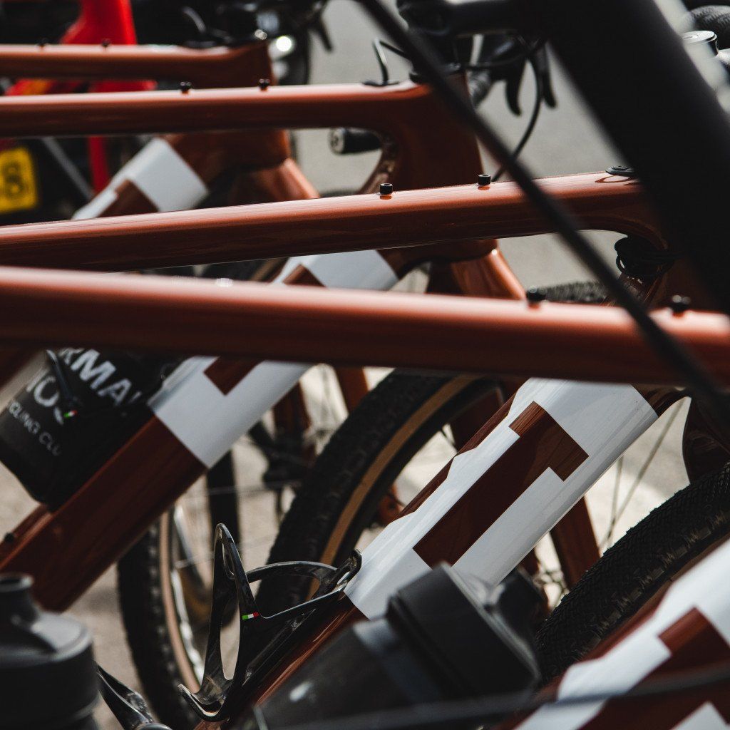 White cycling jerseys with brown geometric patterns hanging on orange bike rack