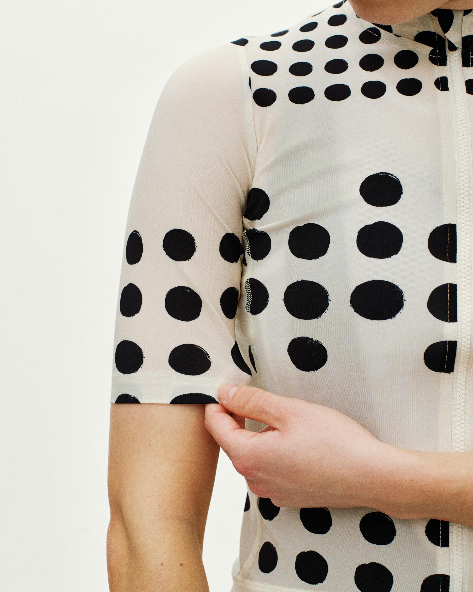 Off White Essential women's cycling jersey, detail view on model with black polka dot print and front zip