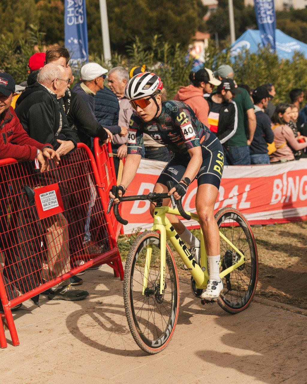 Cyclist in black racing kit competing in cyclocross race on yellow bike