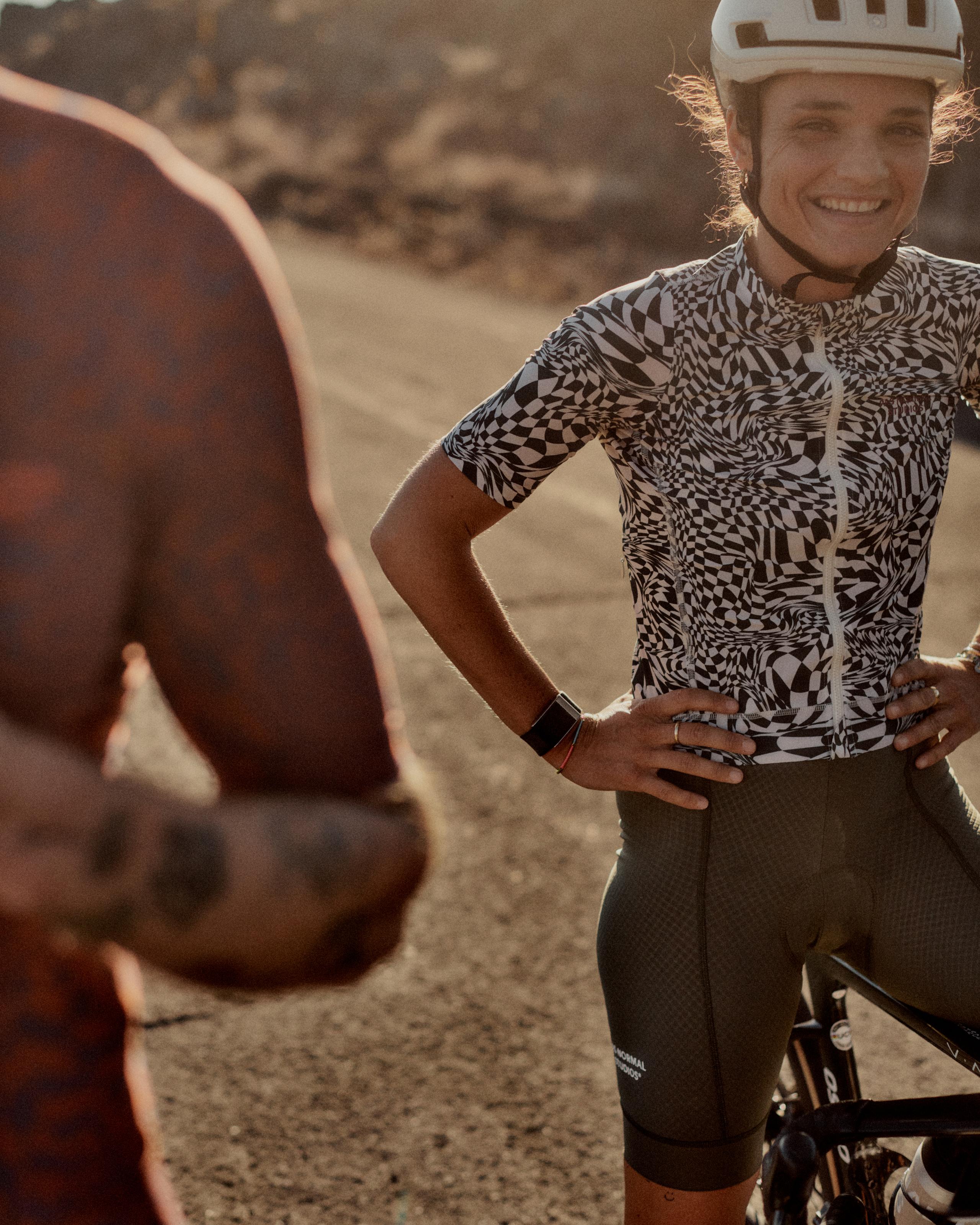 Model wearing white jersey with black geometric pattern and dark cycling shorts on road