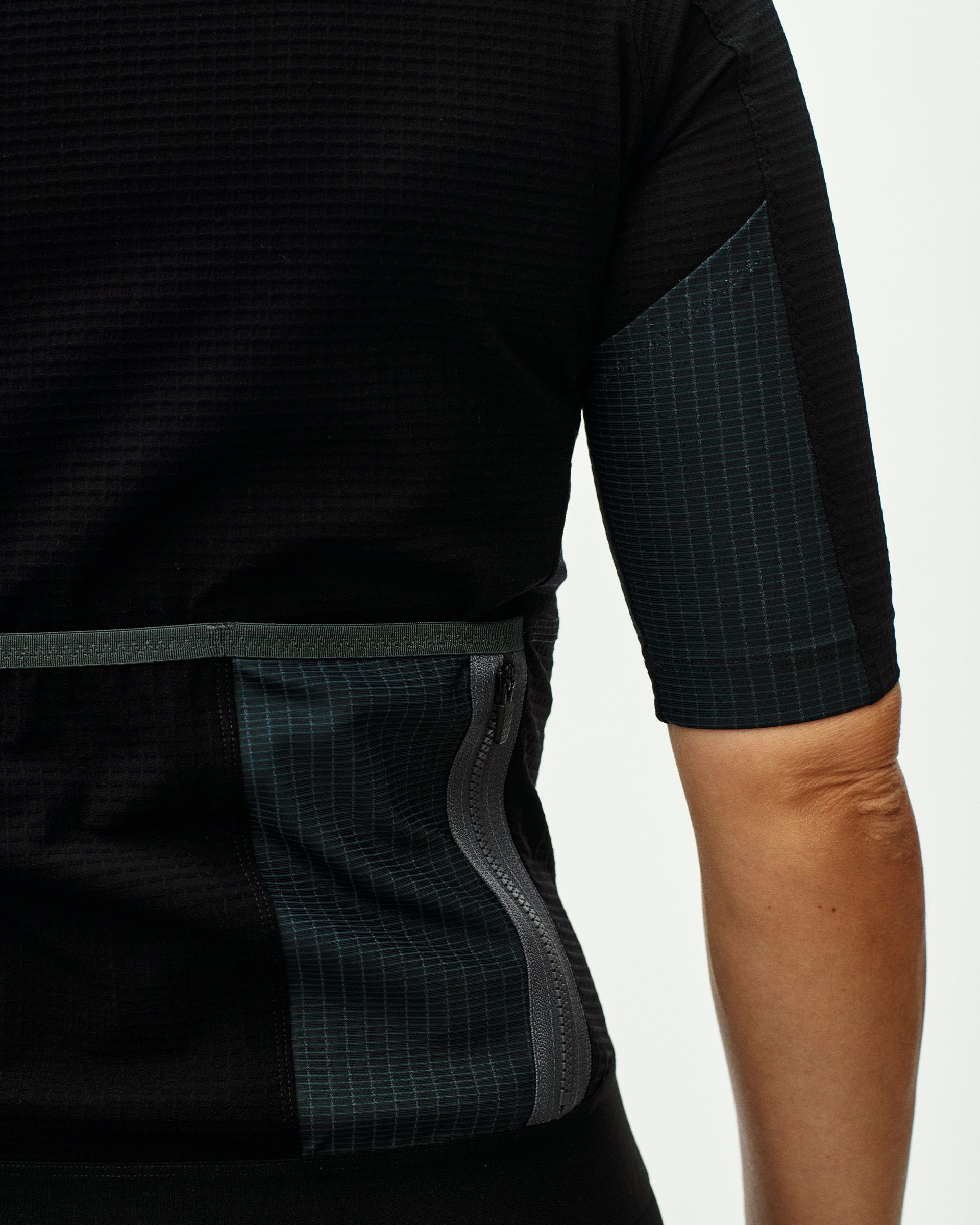 Black Escapism cycling jersey on model with green grid pattern panels and rear pocket