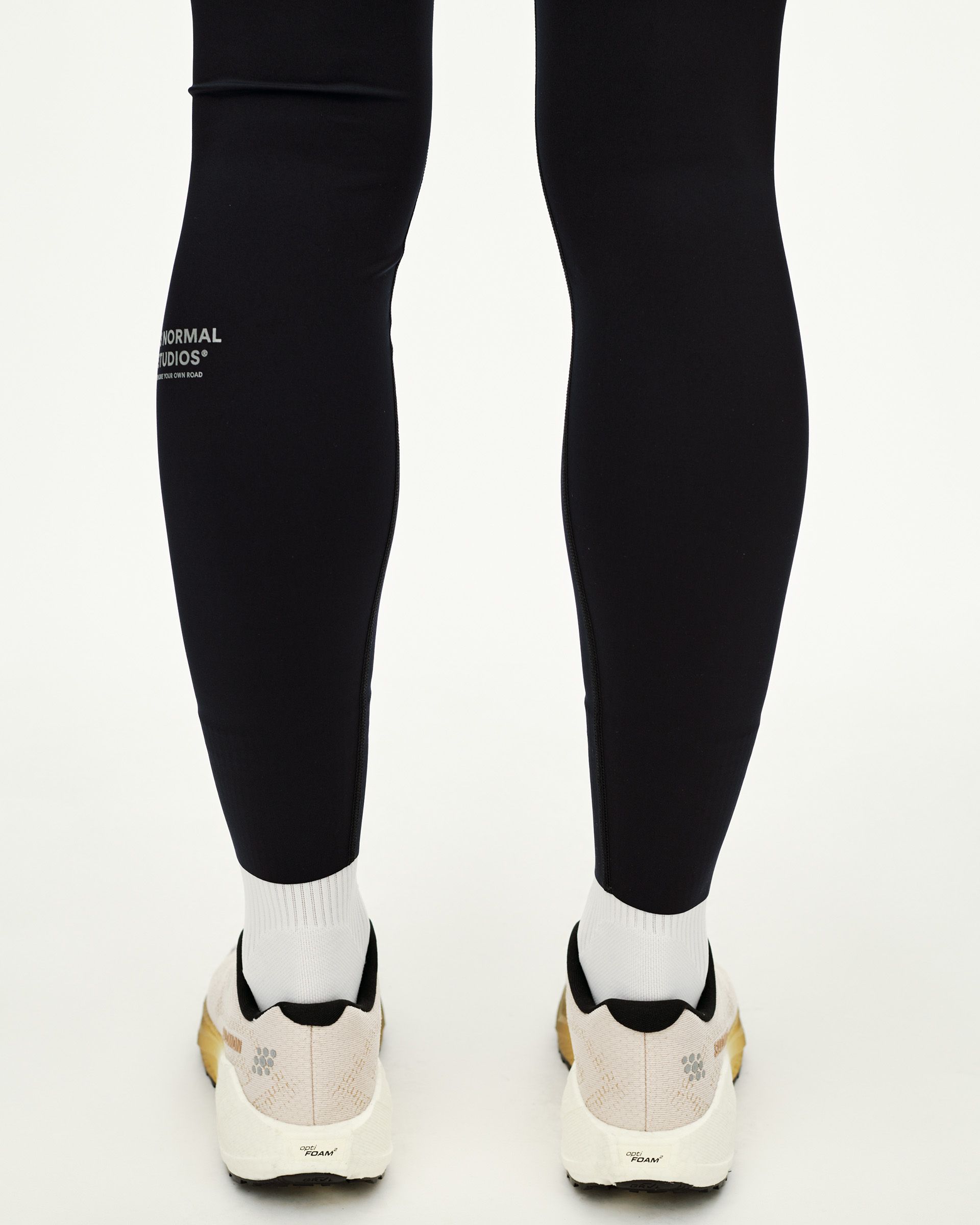 Black Balance long tights on model, rear view with reflective calf logo