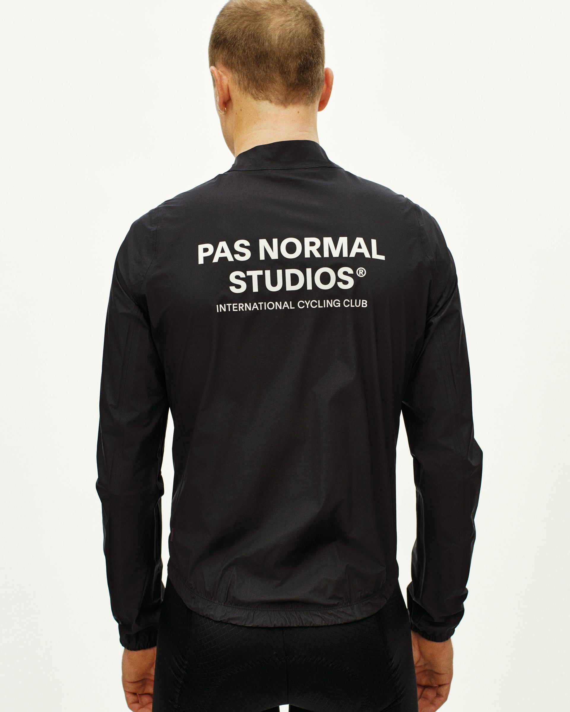 Black Mechanism rain jacket on model, rear view with white brand logo