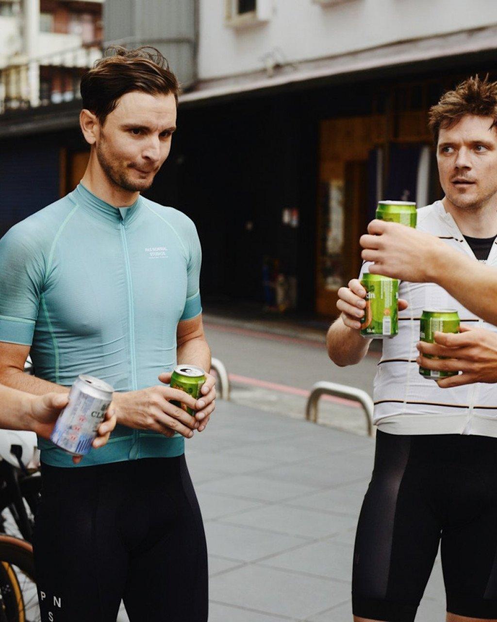 Model wearing light blue cycling jersey with chest branding standing with friend on urban street