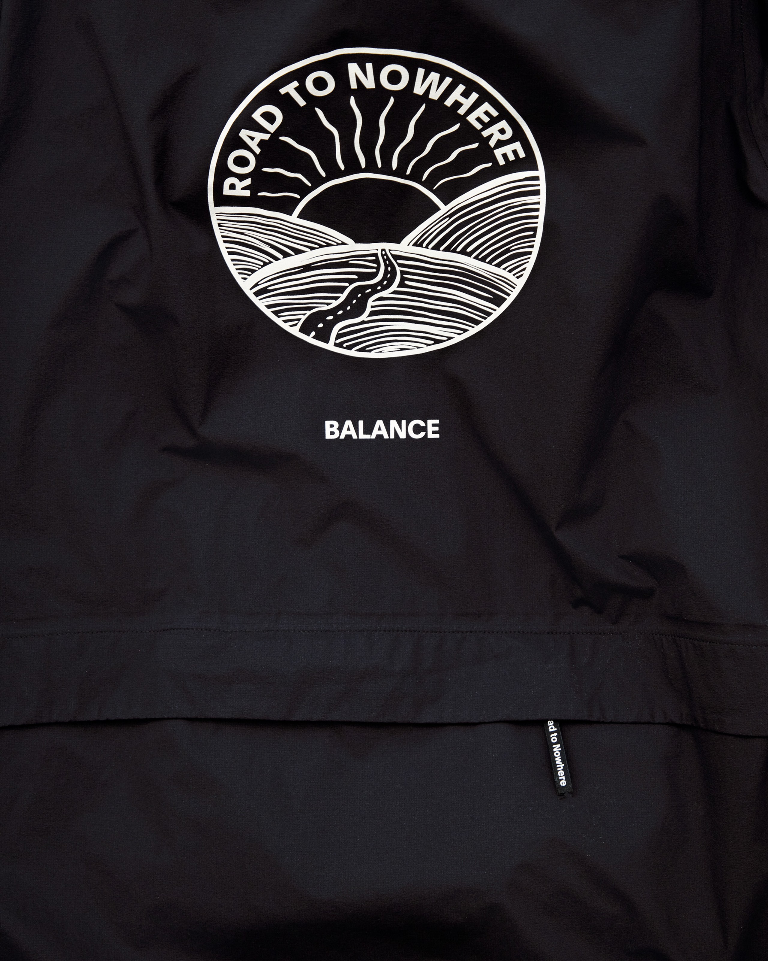 Black cycling jacket with circular "Road to Nowhere" graphic featuring sun and winding road design