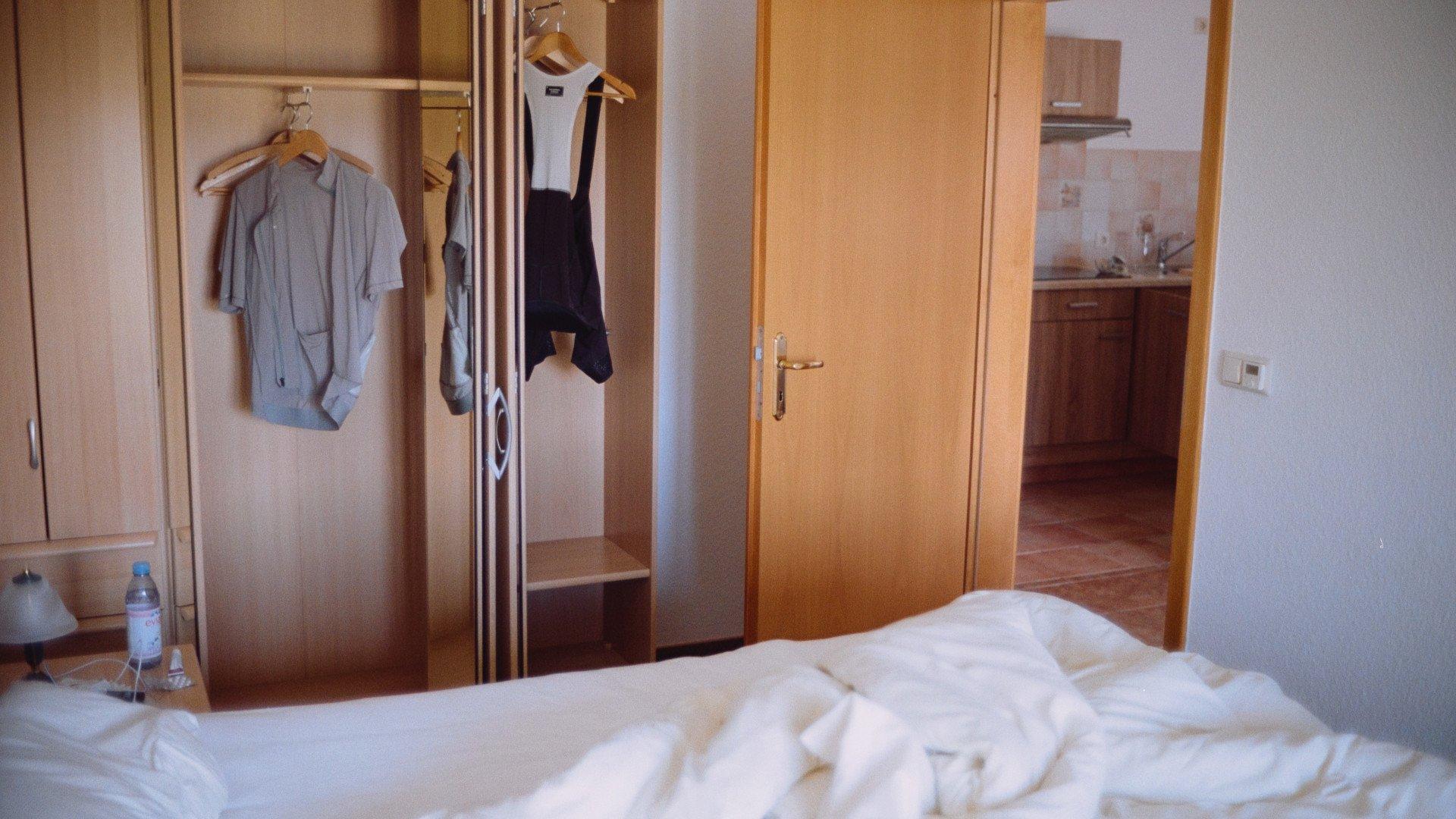 Cycling apparel hanging in hotel wardrobe with light blue jersey and black bib shorts