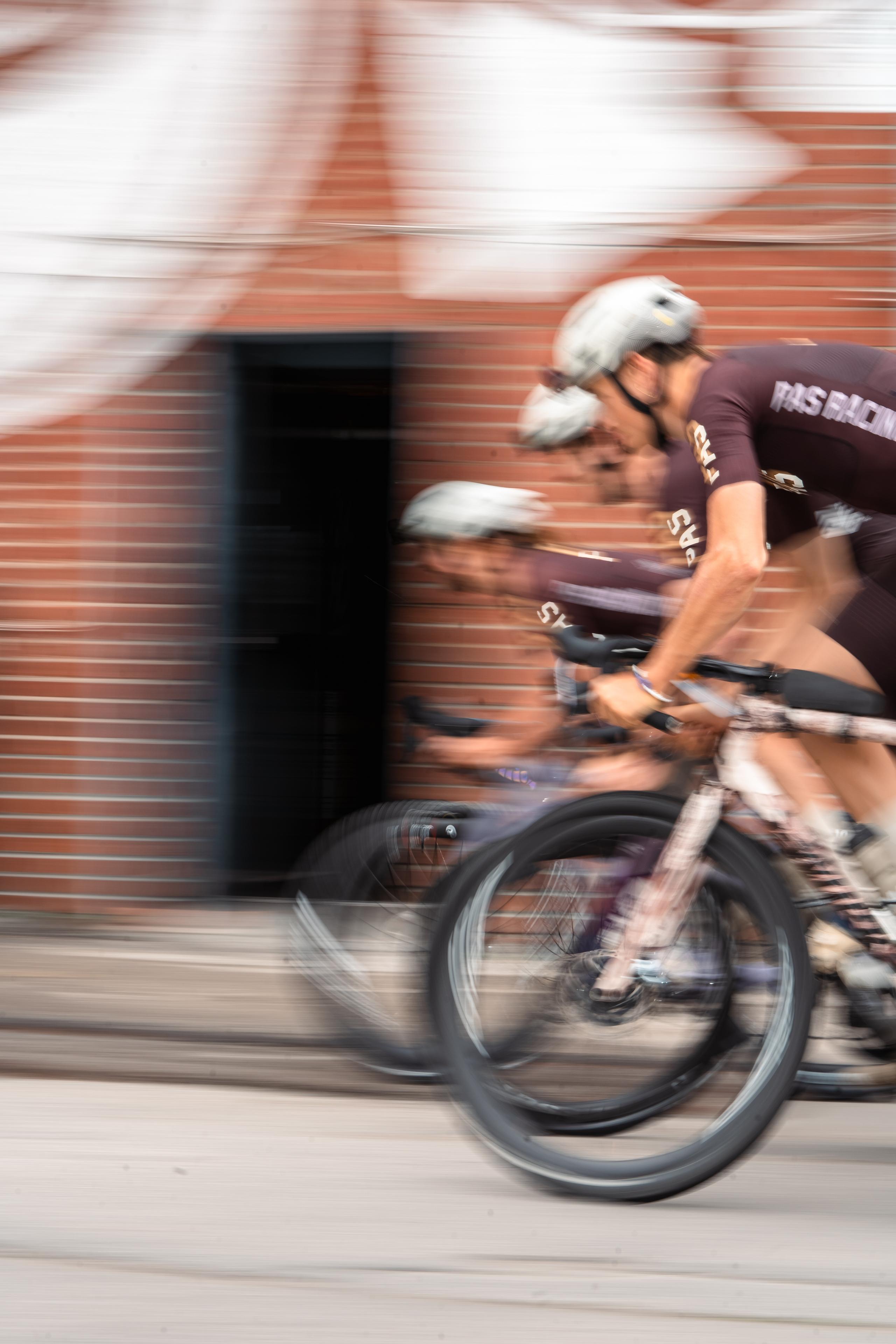 Model wearing brown cycling kit on time trial bike with motion blur effect