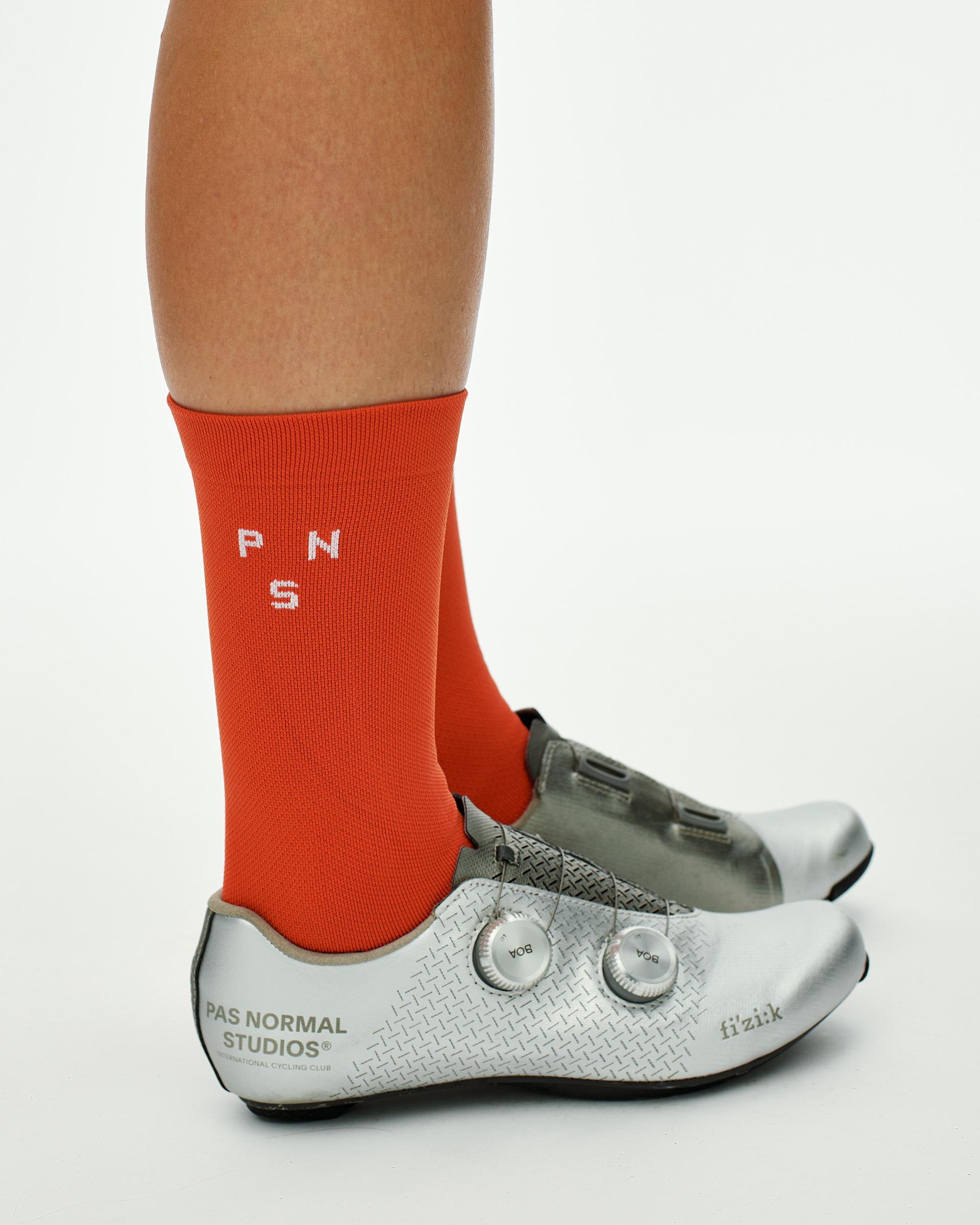 Hibiscus Orange Essential cycling socks on model, side view with white knit logo