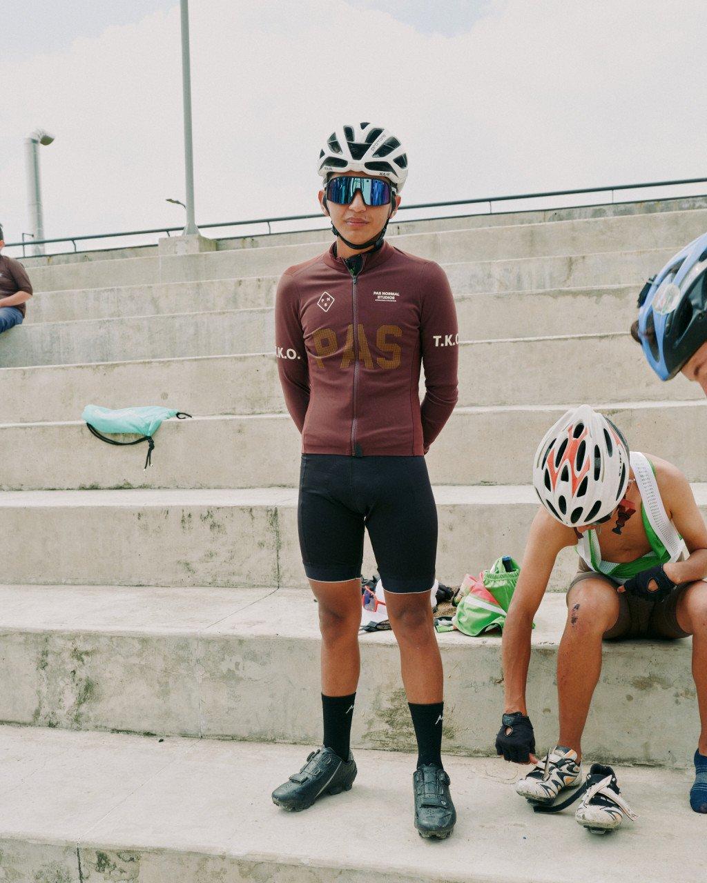 Model wearing burgundy long sleeve cycling jersey with chest lettering and black bib shorts