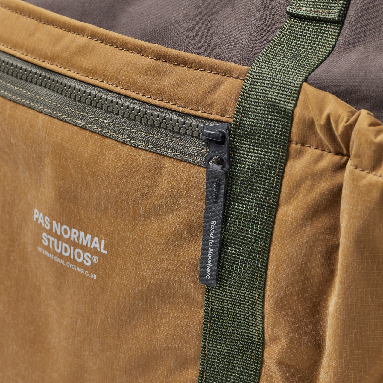 Light Brown Porter-Yoshida tote bag, detail view of front zip pocket with green webbing strap and branded zip pull