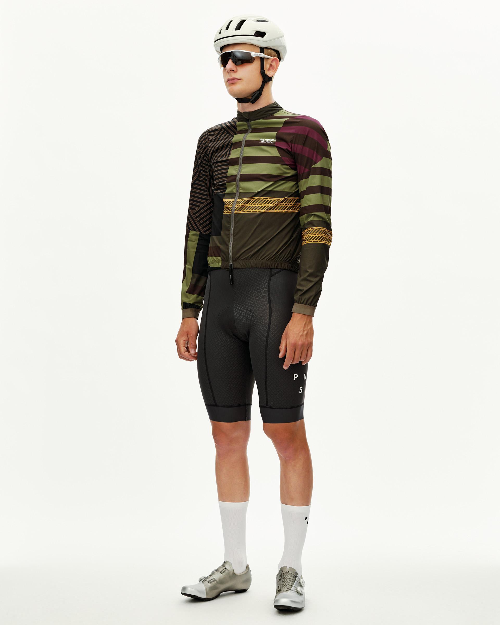 International Green Mechanism Stow Away cycling jacket on model, three-quarter front view with multicolor graphic print