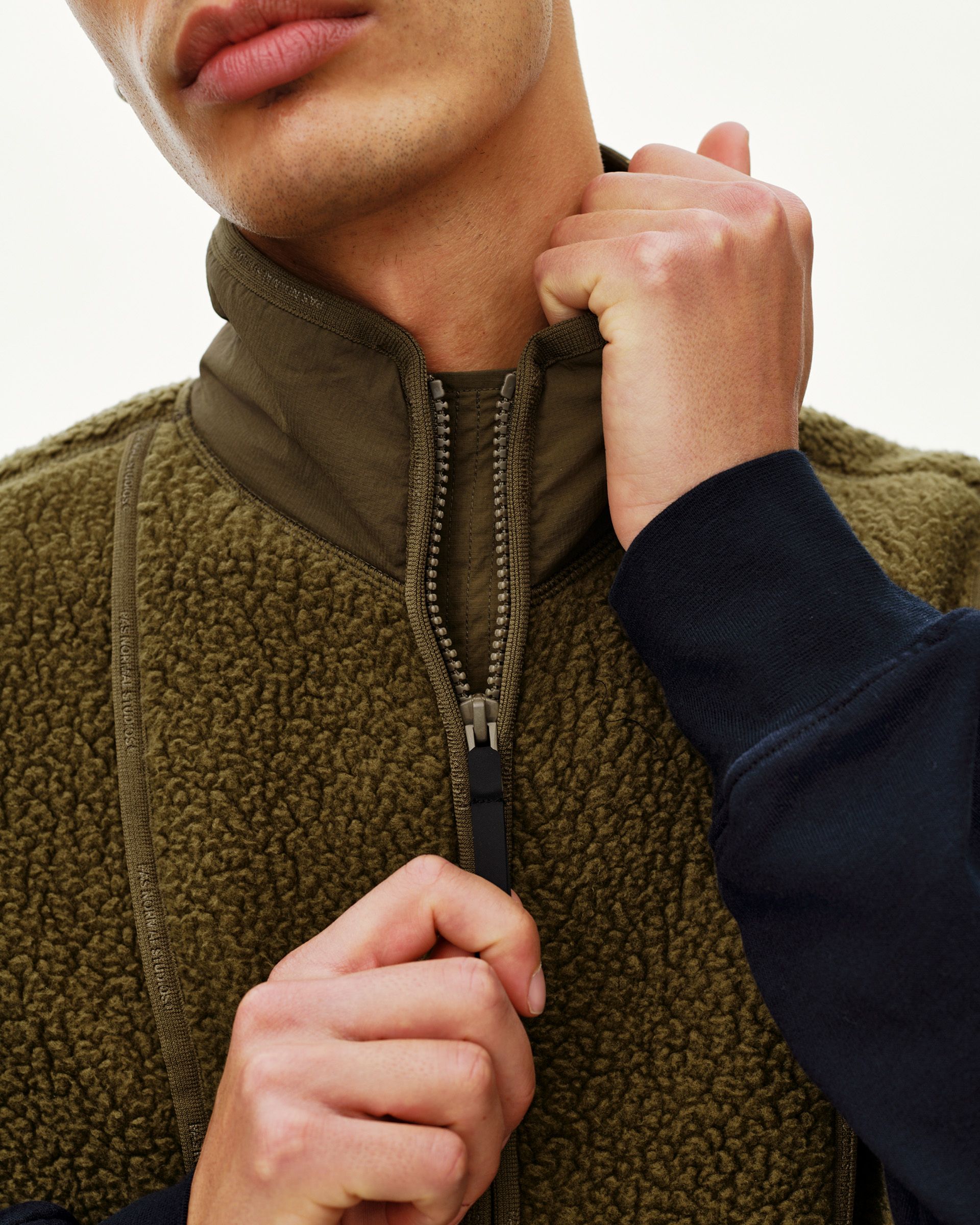 Deep Olive Off-Race Pile Fleece vest on model, detail view of full-length zip and sherpa texture