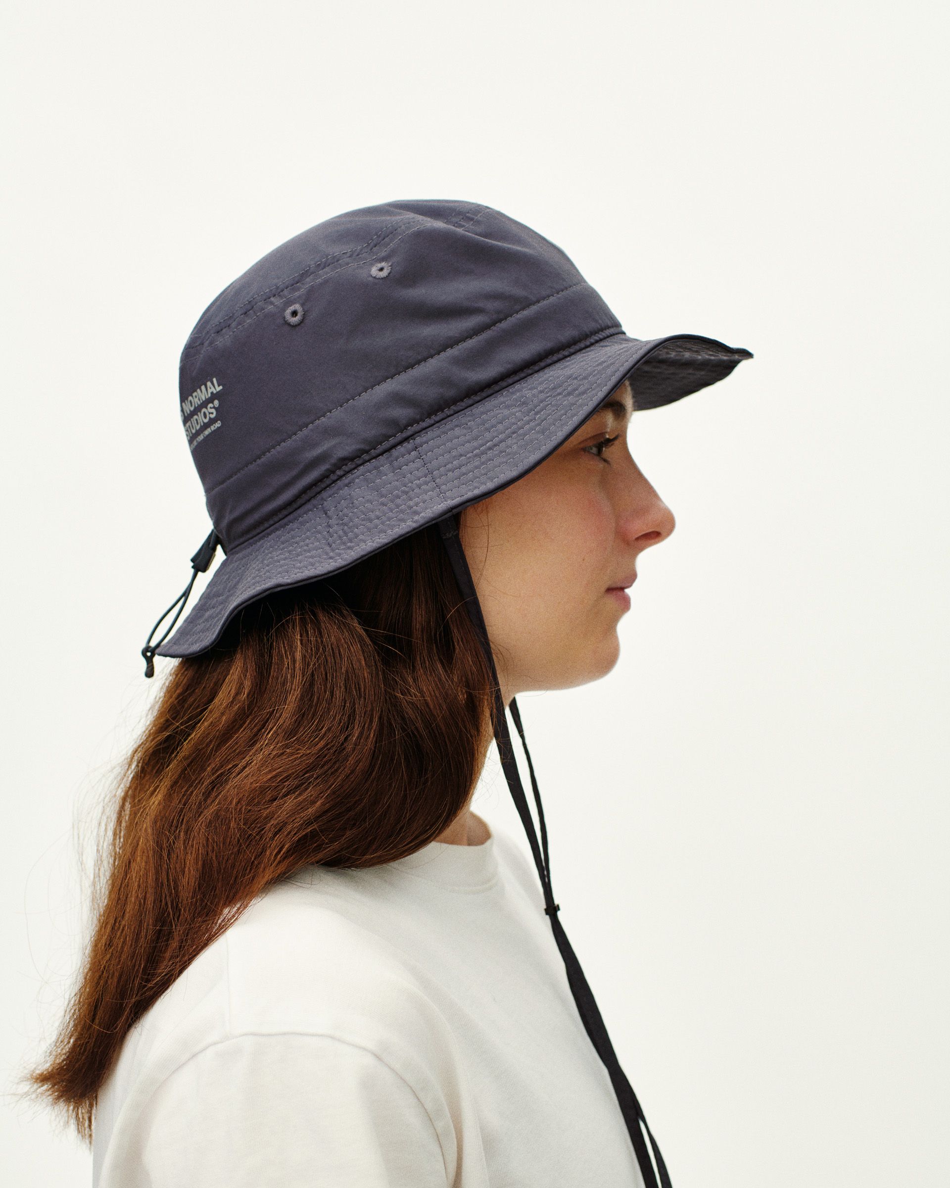 Grey Off-Race Tech bucket hat on model, side view with chin strap and white logo