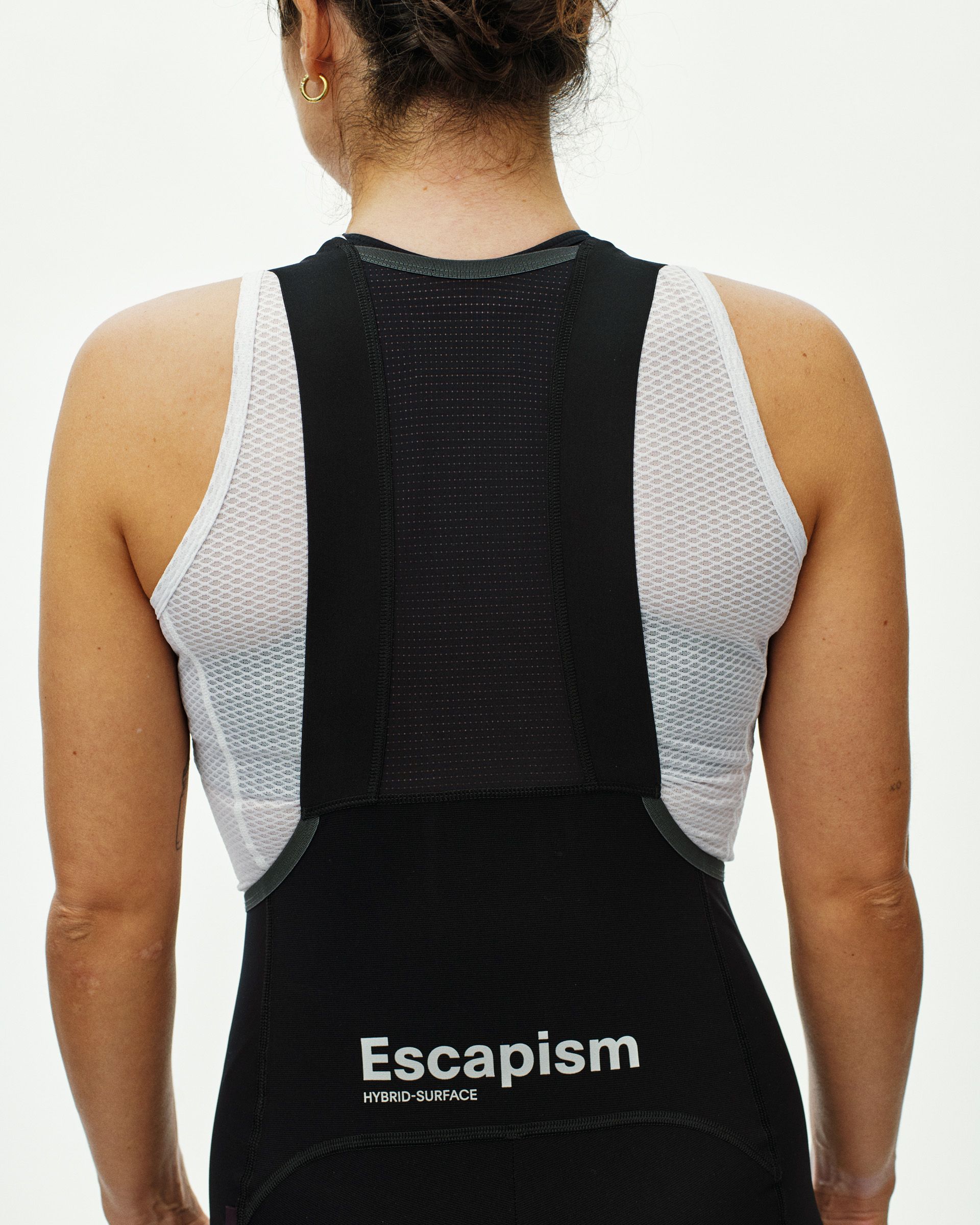 Black Escapism cargo bibs on model, rear view with white mesh side panels and perforated back panel