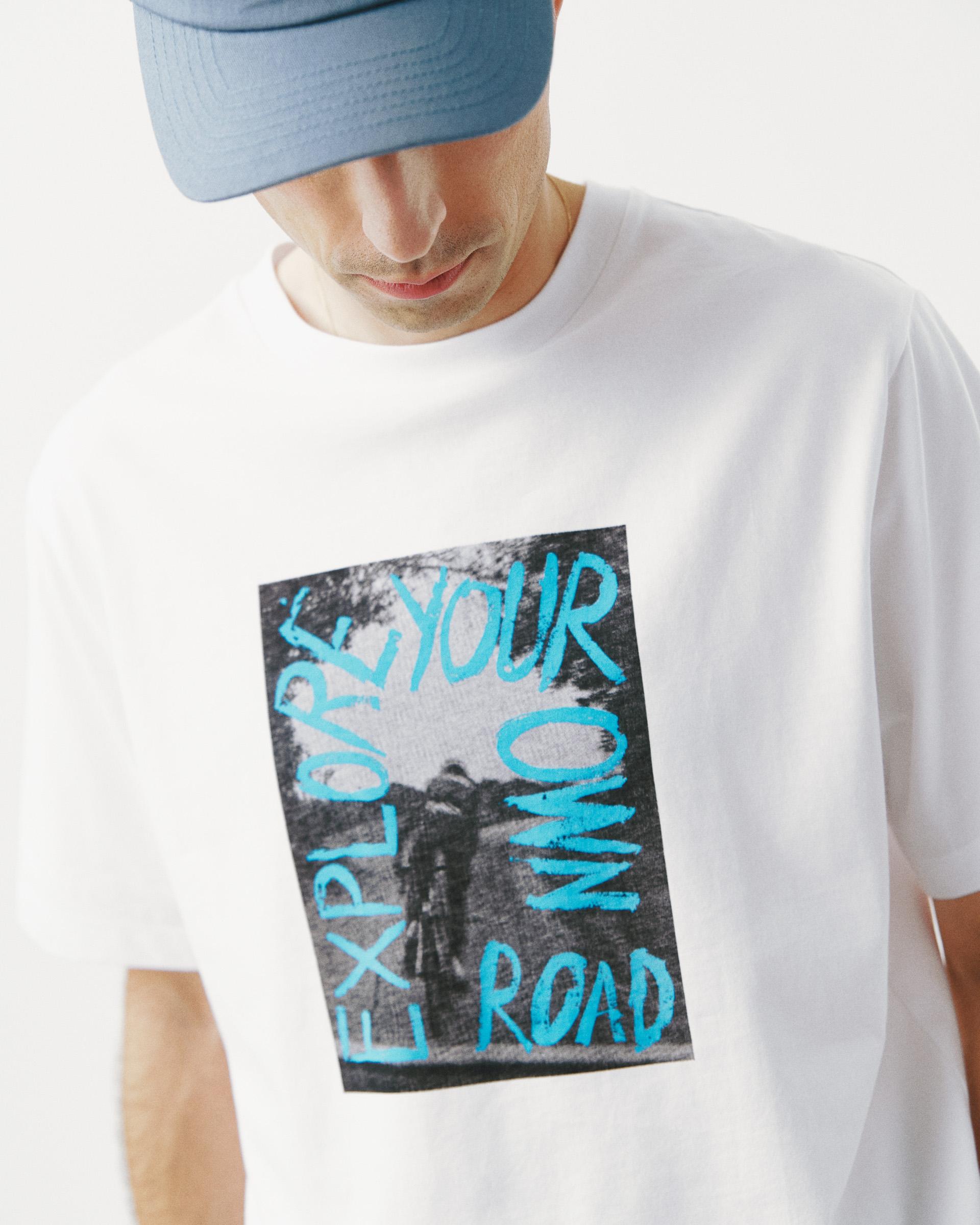 White Off-Race Graphic t-shirt on model with blue "EXPLORE YOUR OWN ROAD" chest print