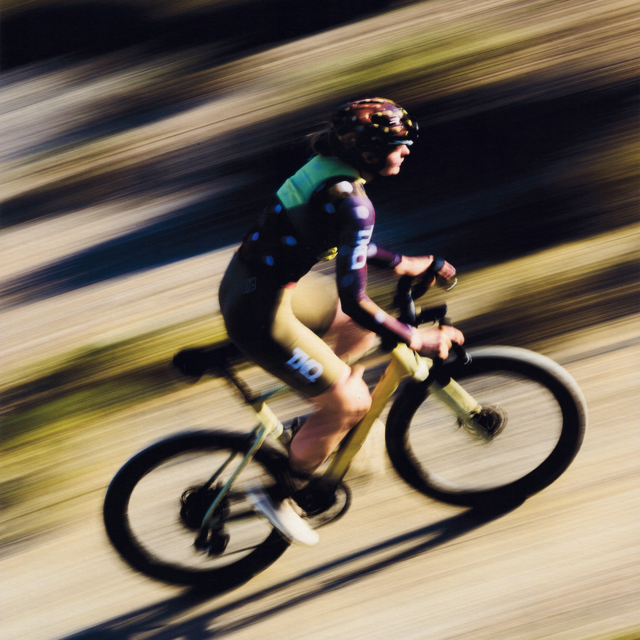 Model wearing colorful cycling kit in motion blur on time trial bike