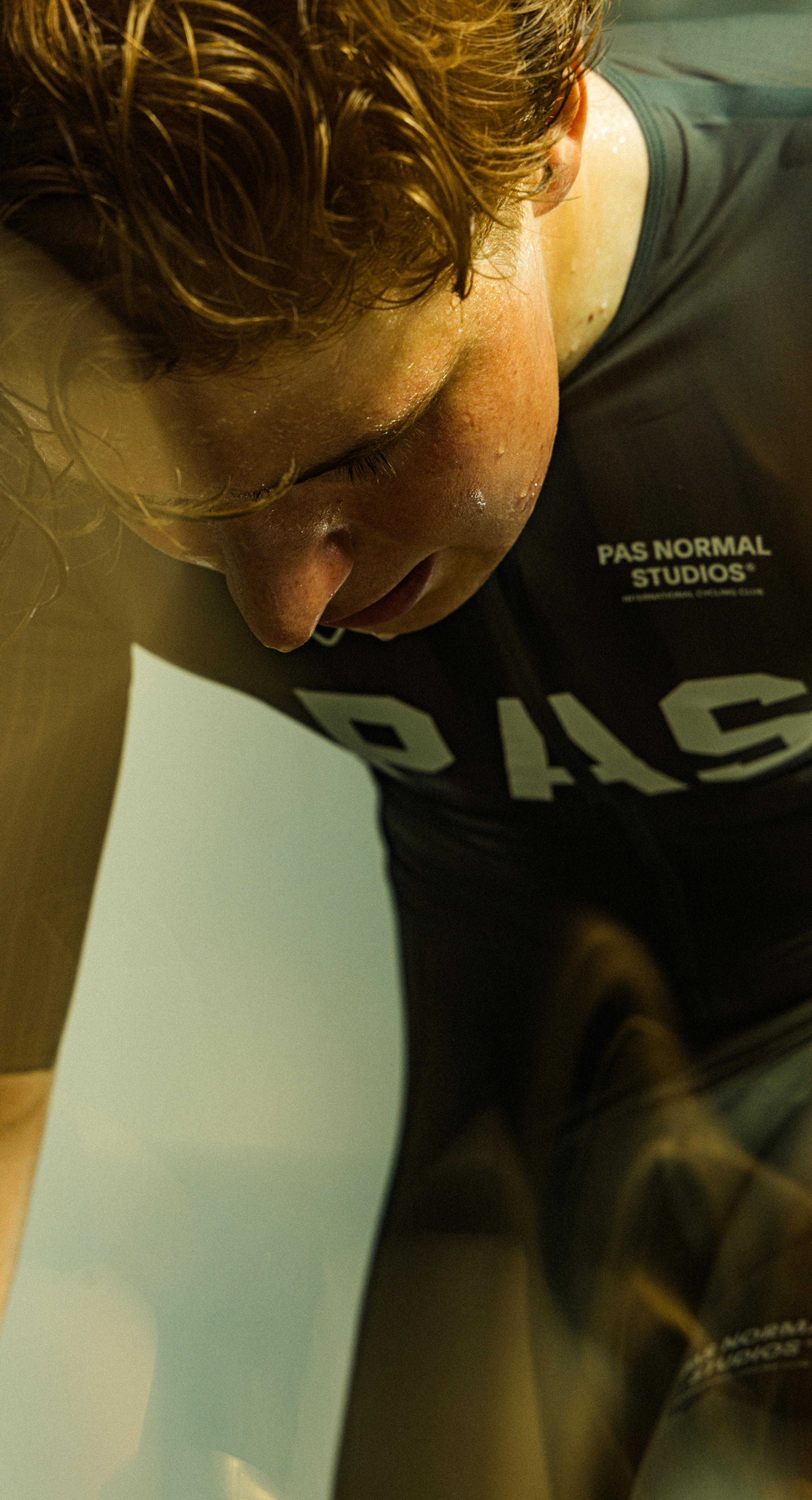 Model wearing black PAS collection jersey with branding, close-up shot showing perspiration during exercise