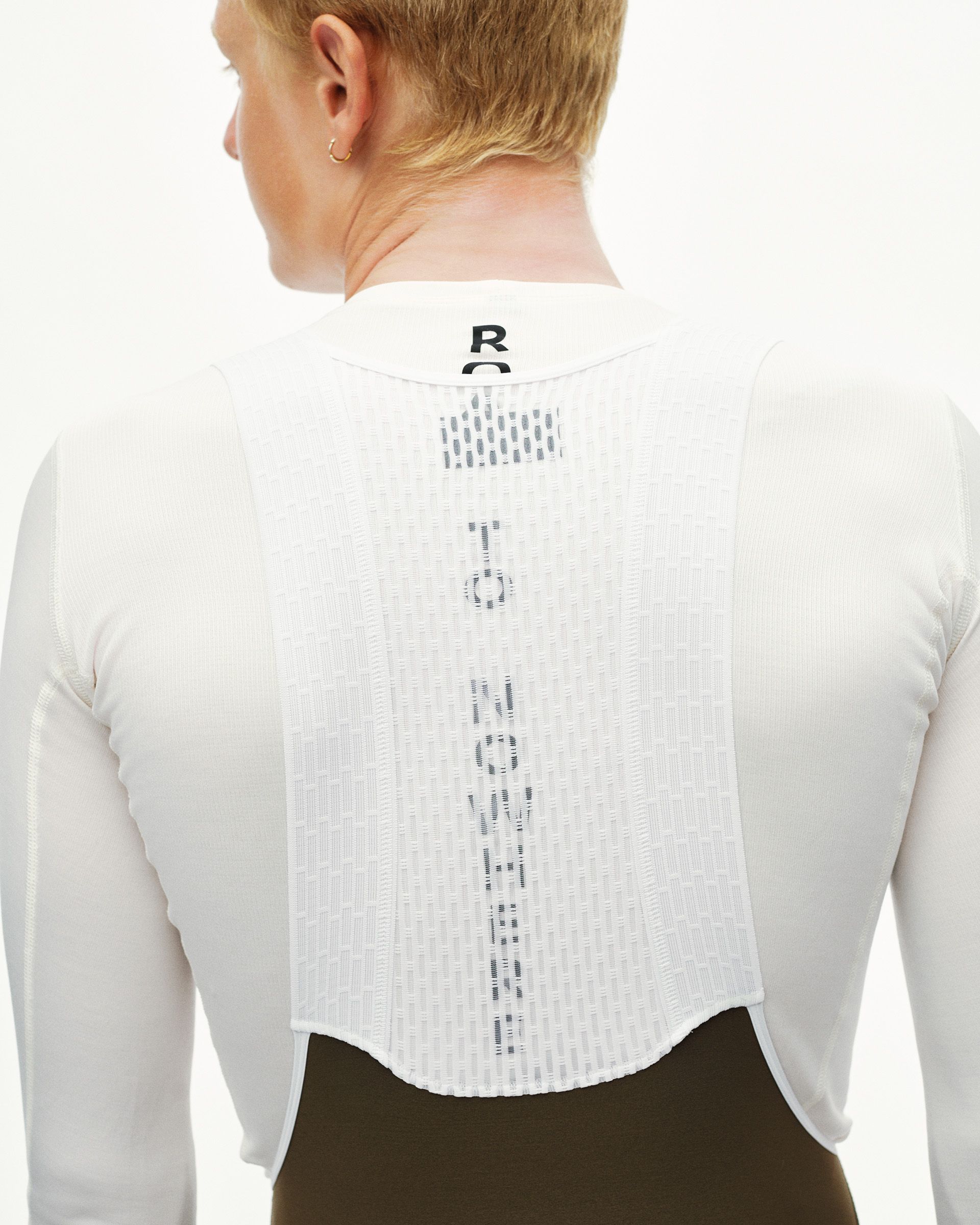 Dark Earth Thermal long cycling bibs shown from behind on a model wearing a long-sleeve base layer top over the bibs
