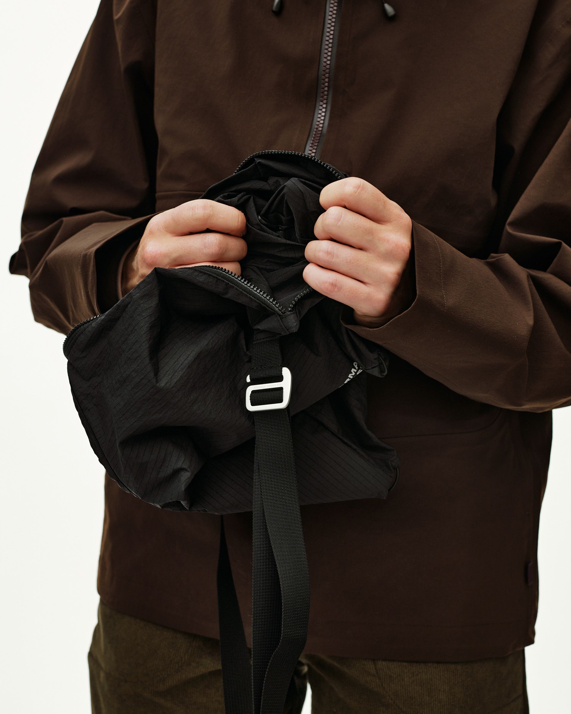 Black Off-Race Tech Musette 2.0 bag, detail view held open on model showing black interior and strap buckle