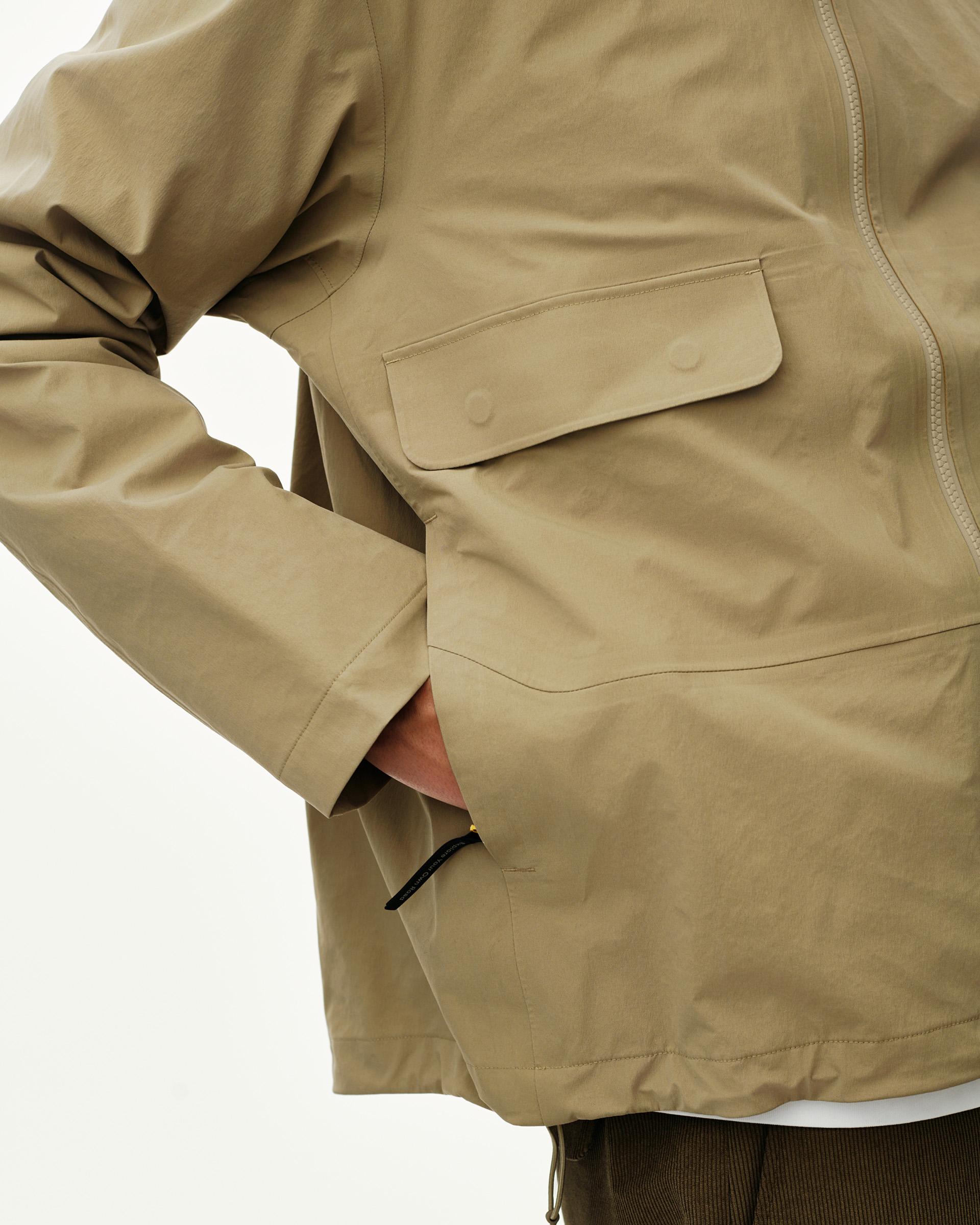Dusty Earth khaki Off-Race 3L Shell jacket on model, side detail showing chest flap pocket and zip hand pocket