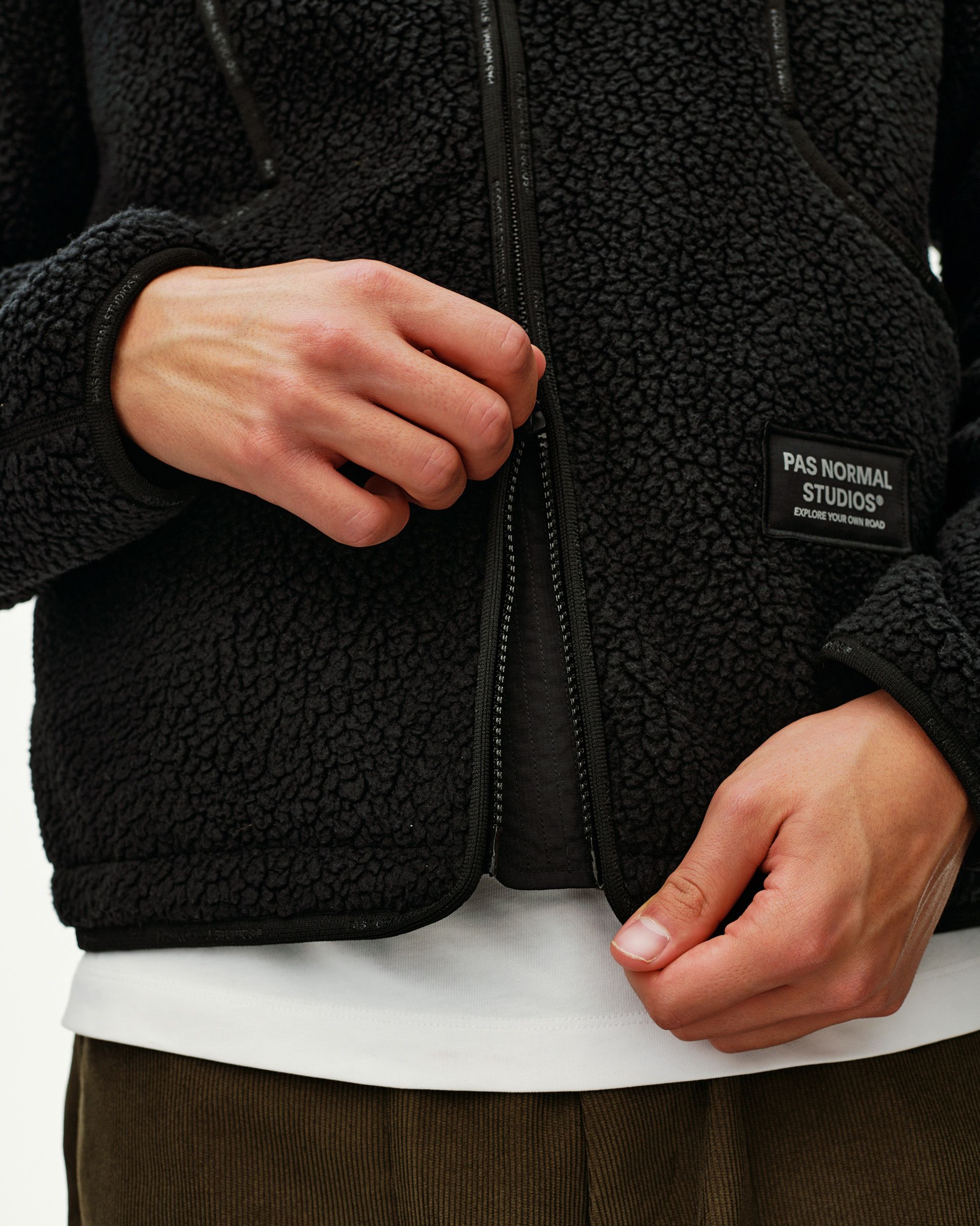 Black Off-Race Pile Fleece jacket, detail view on model showing open front zip and branded patch label