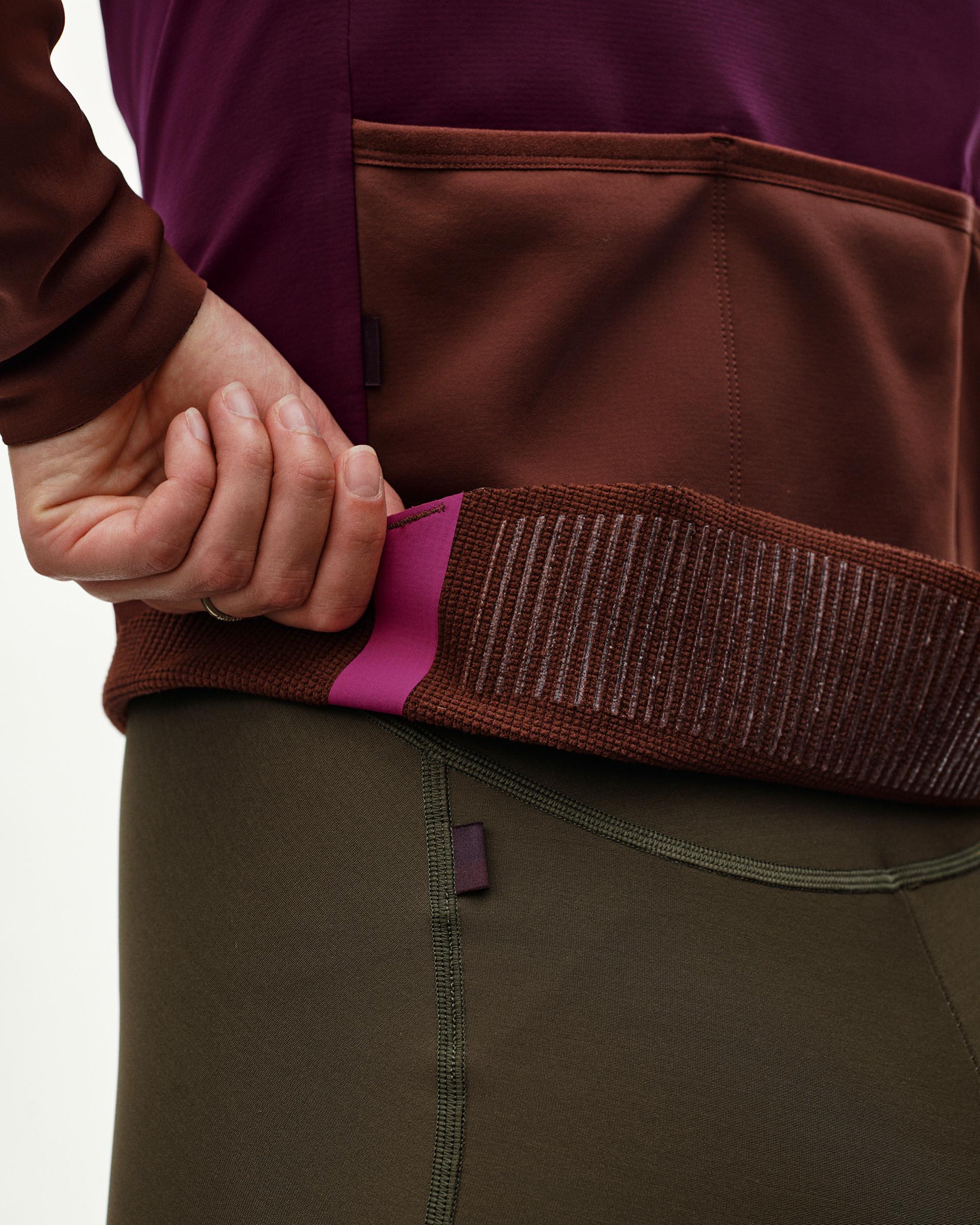 Dark Purple PAS Mechanism women's cycling jacket, detail view on model showing ribbed hem band and rear pocket access