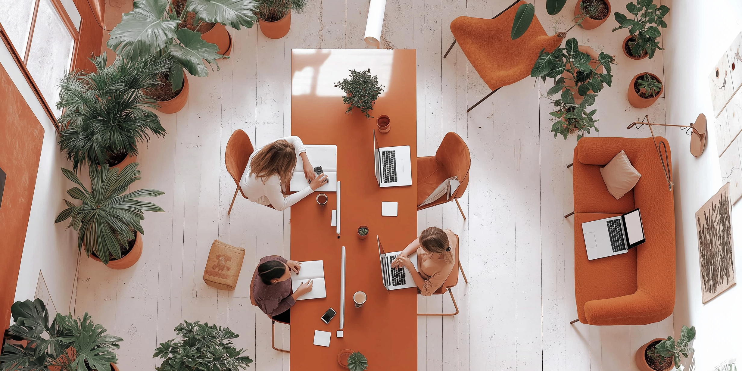 a group of people are sitting at a table with laptops