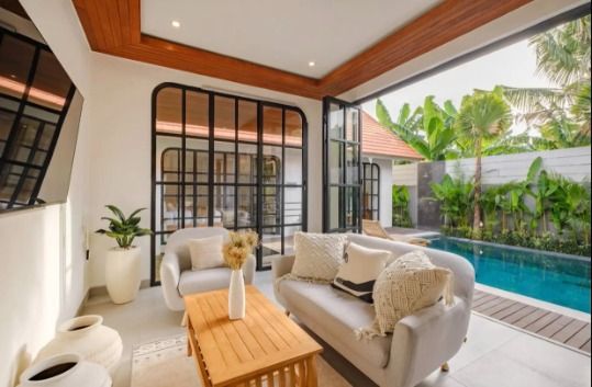 Open-plan living area of a Bali villa with sofas, glass doors and a private pool