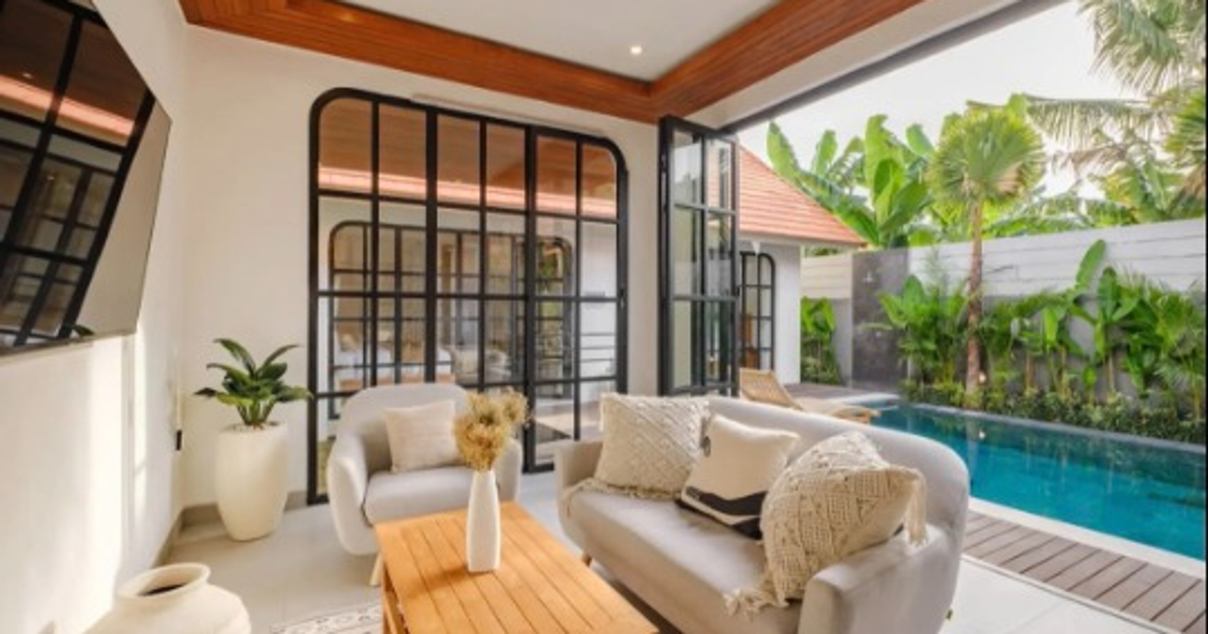 Open-plan living area of a Bali villa with sofas, glass doors and a private pool